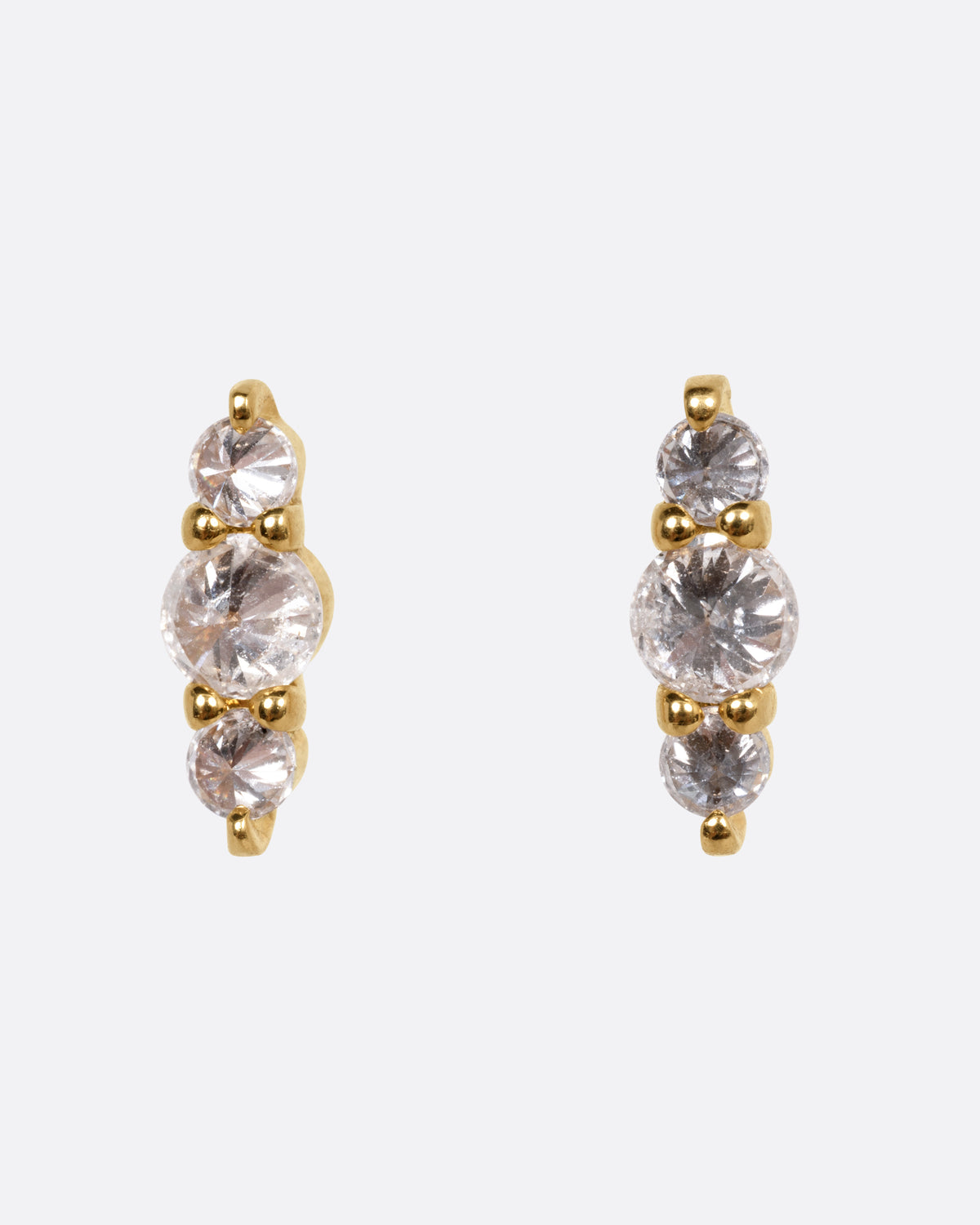 A pair of yellow gold stud earrings, each with three stacked diamonds, shown from the front.