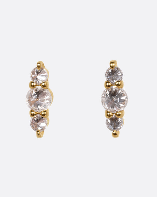 A pair of yellow gold stud earrings, each with three stacked diamonds, shown from the front.