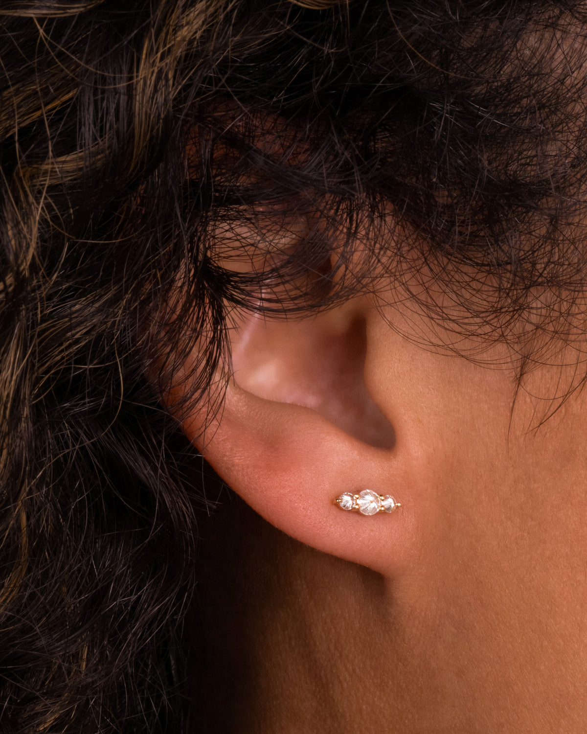 Yellow gold reverse-set diamond bar stud earrings worn on an ear