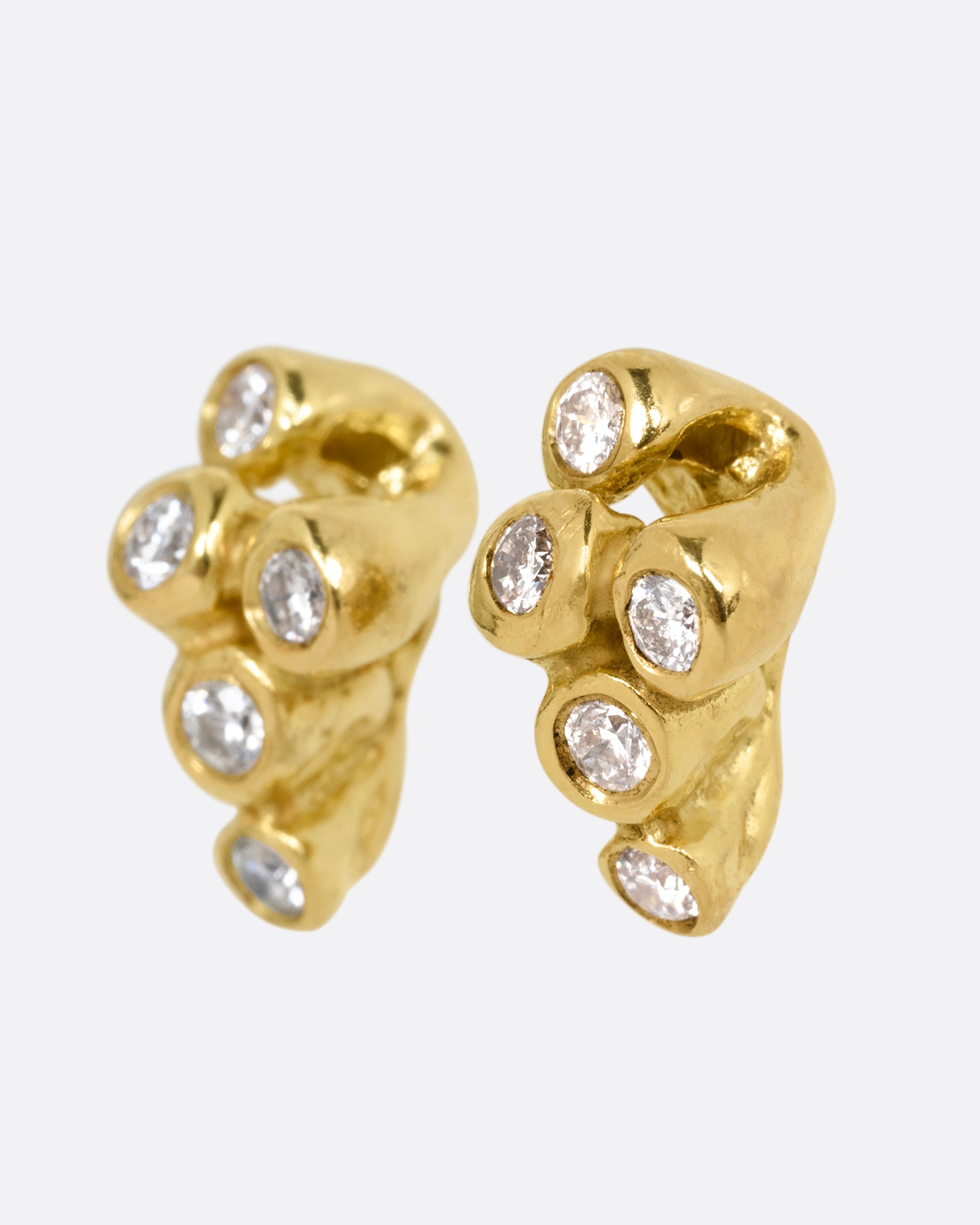 A pair of yellow gold earrings with sea anemone shaped clusters of diamonds. Shown from the side.