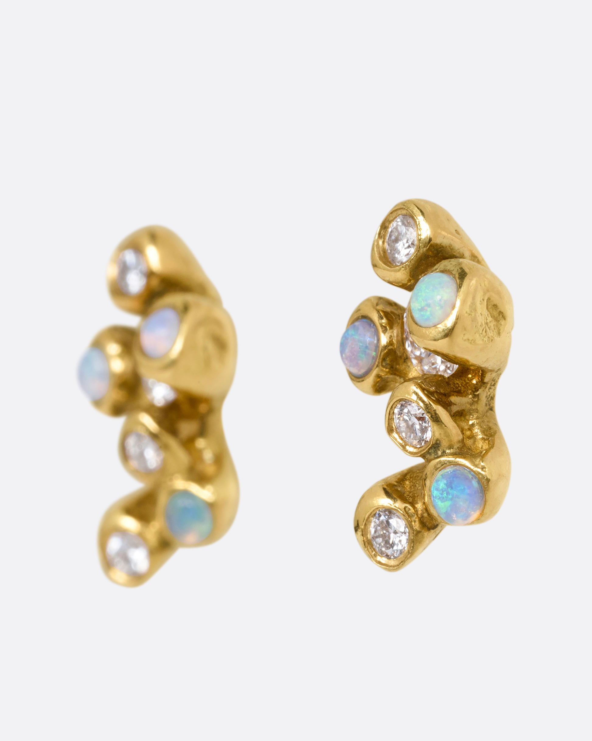 A pair of yellow gold stud earrings with clusters of diamonds and opals. Shown from the side.