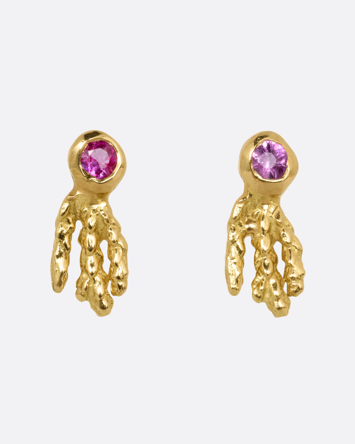 A pair of yellow gold earrings with pink sapphires and gold kelp- like tails. Shown from the front.