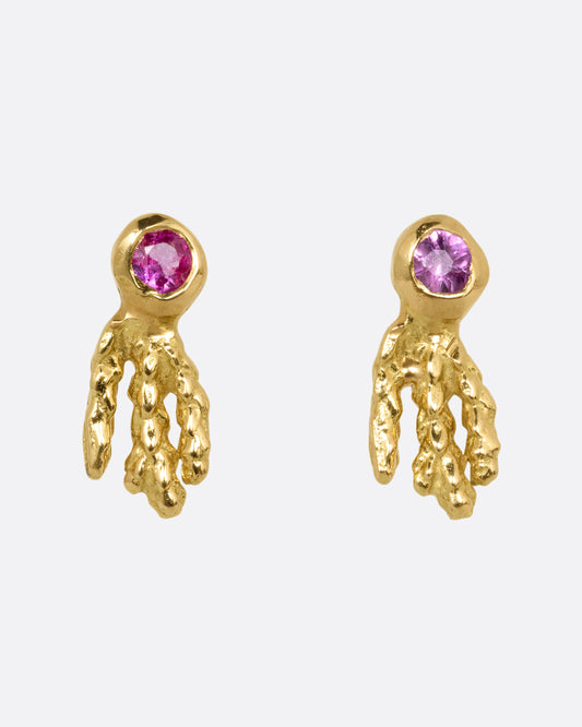 A pair of yellow gold earrings with pink sapphires and gold kelp- like tails. Shown from the front.
