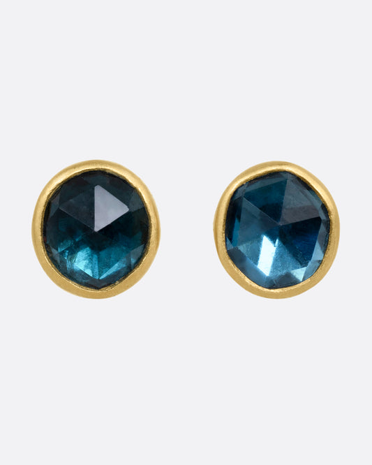 A pair of yellow gold stud earrings with blue green tourmalines. Shown from the front.