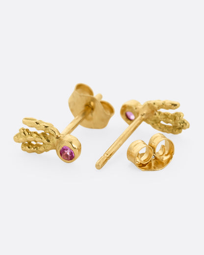 A pair of yellow gold earrings with pink sapphires and gold kelp- like tails. One earring is shown from the front, the other open from the back.
