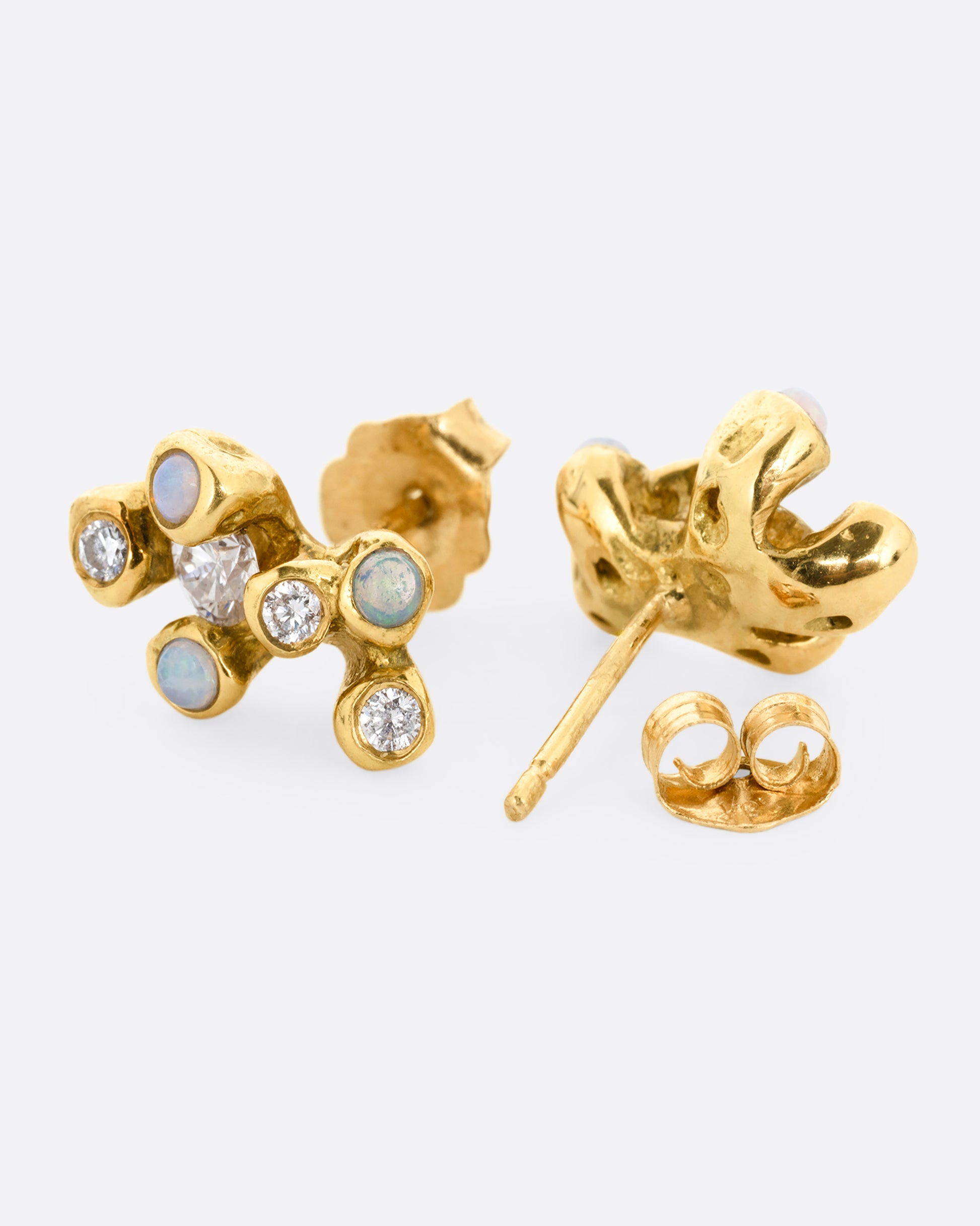 A pair of yellow gold stud earrings with clusters of diamonds and opals. One earring is shown from the front, the other open from the back.