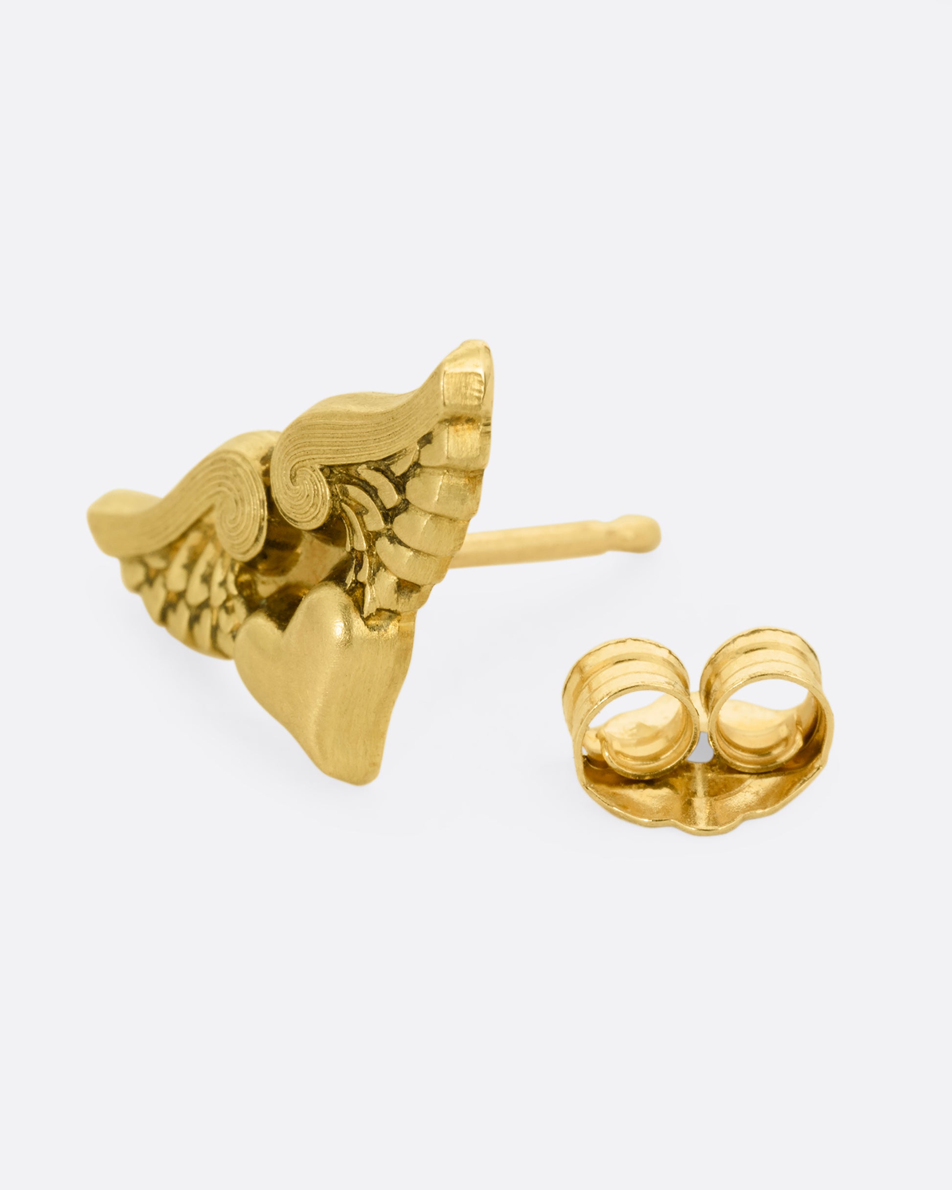 A yellow gold stud earring with a heart with wings. Shown open from the front.