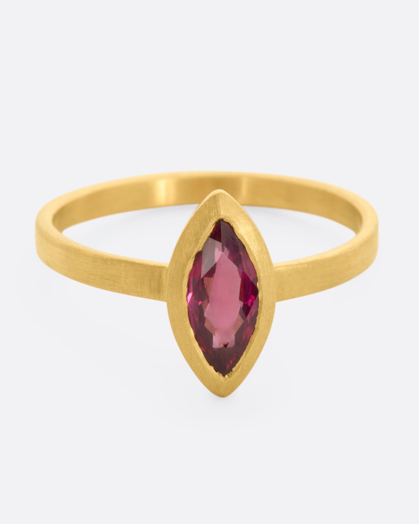 A matte yellow gold ring with a bezel set ruby marquise. View from the front.