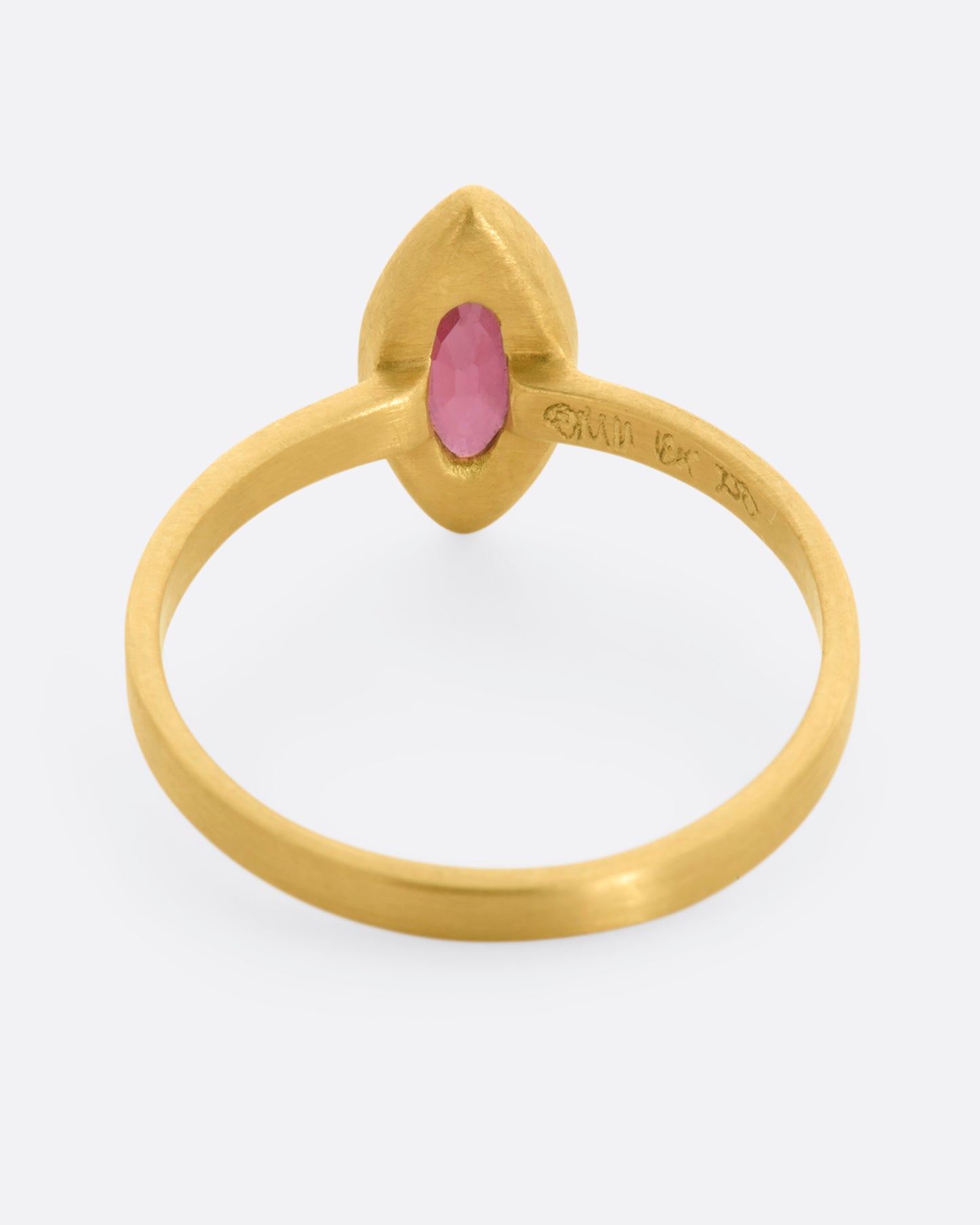 A matte yellow gold ring with a bezel set ruby marquise. View from the back.