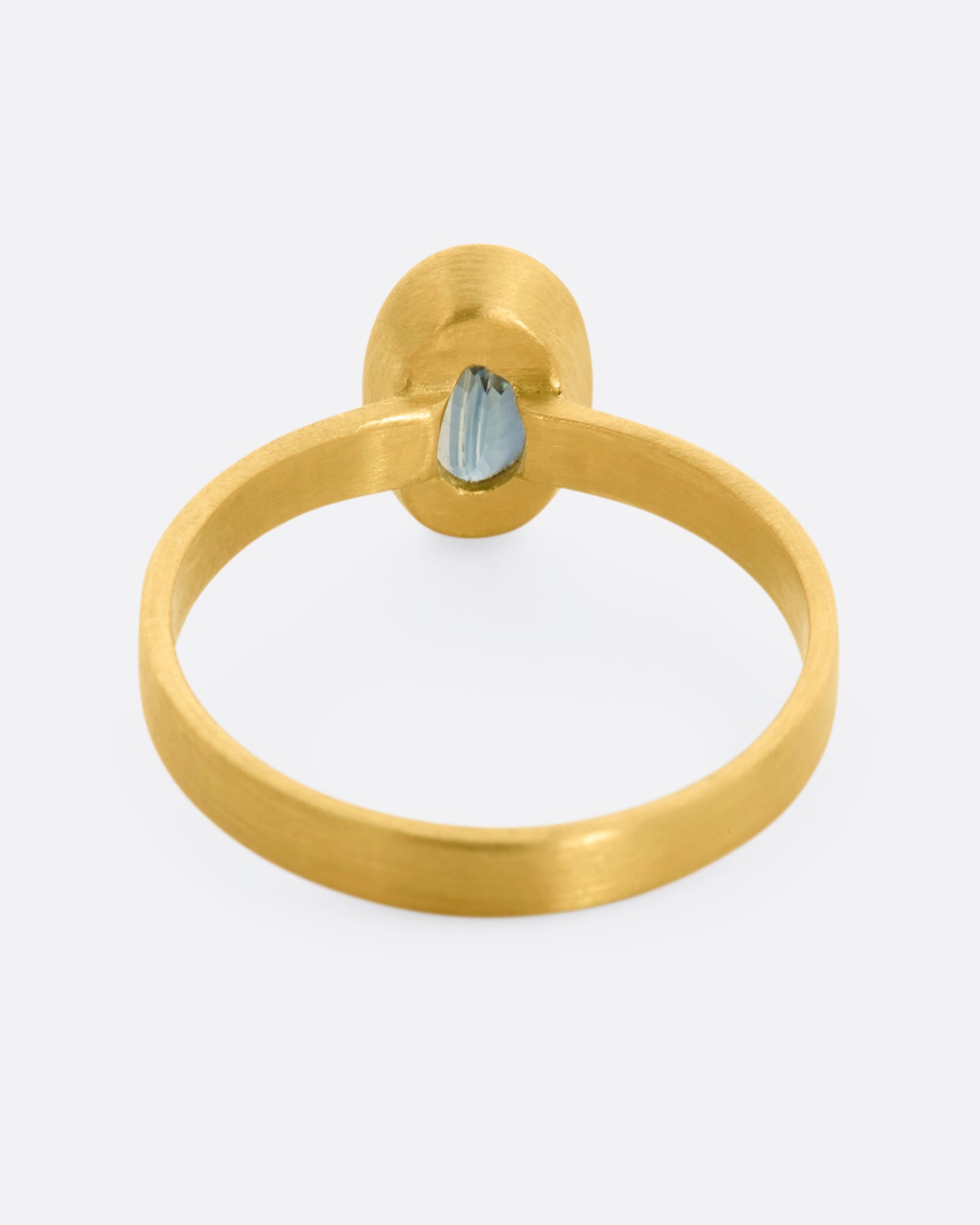 A matte yellow gold ring with an oval blue sapphire. View from the back.