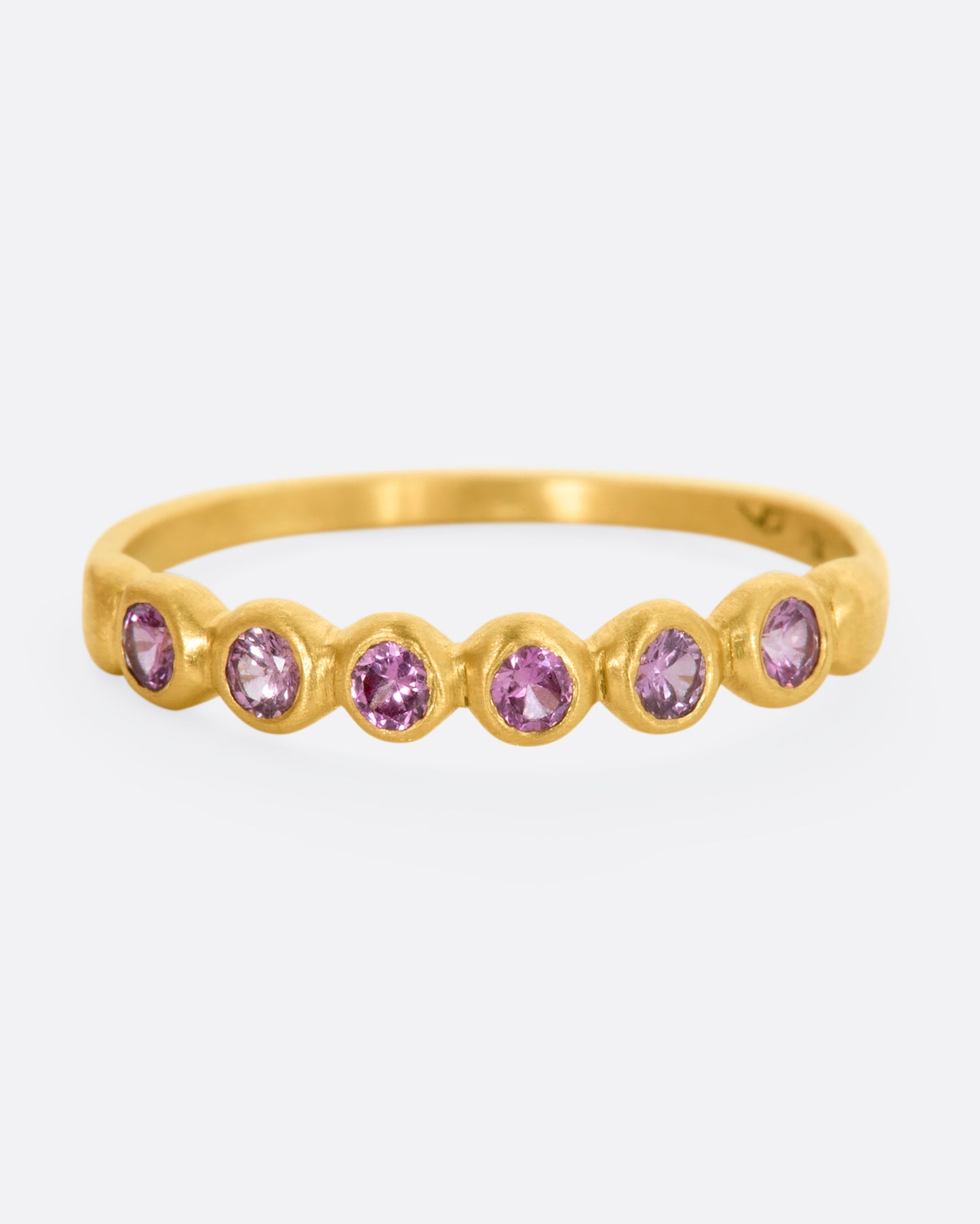 A yellow gold band with a row of pink sapphires. Shown from the front.