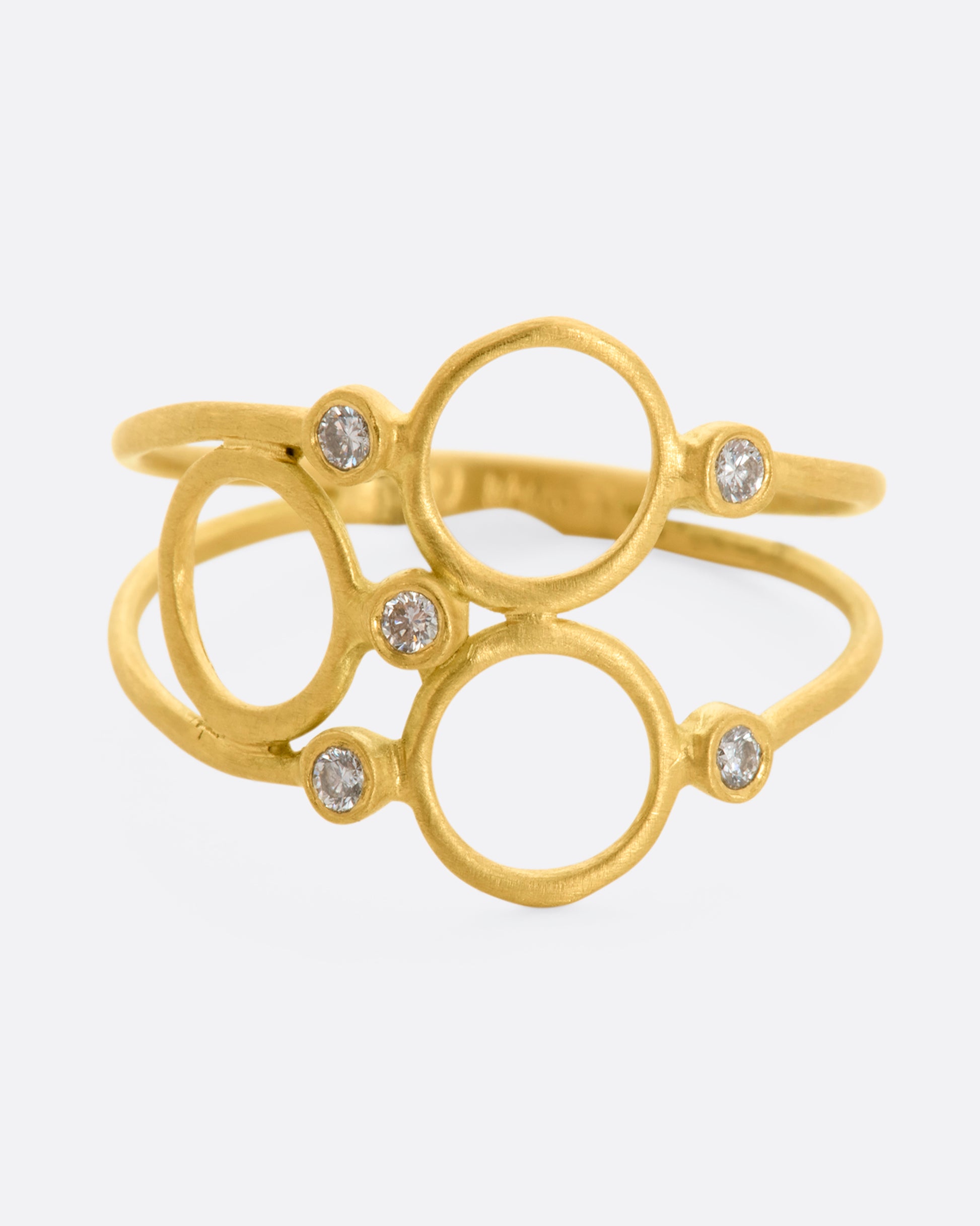 A yellow gold ring with three circles and five diamonds sandwiched between two thin bands. View from the front close up.