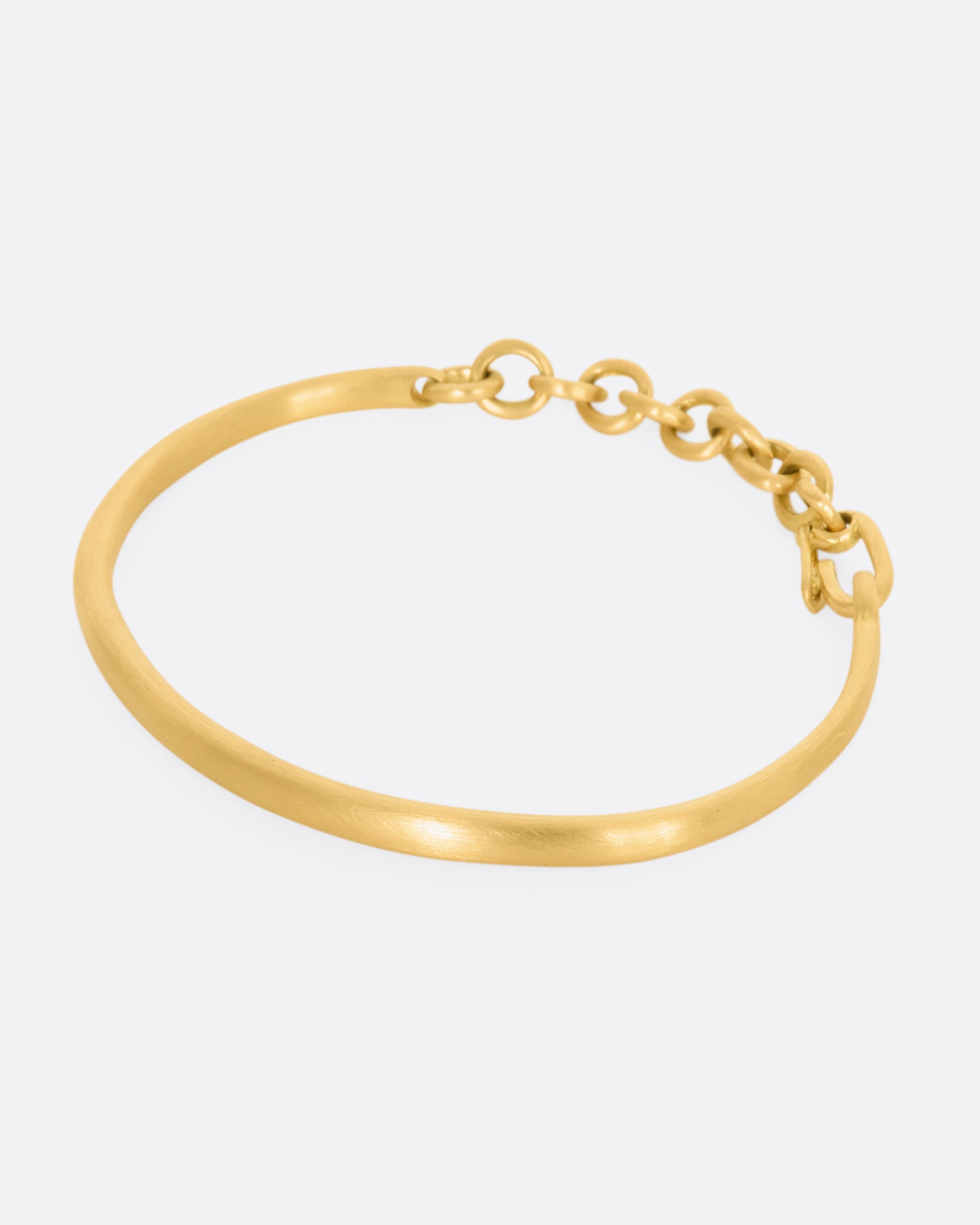 Yellow gold cuff bracelet with a chain closure.