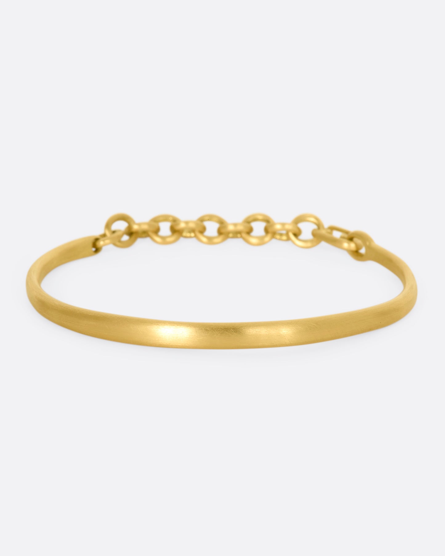 Yellow gold cuff bracelet with a chain closure.