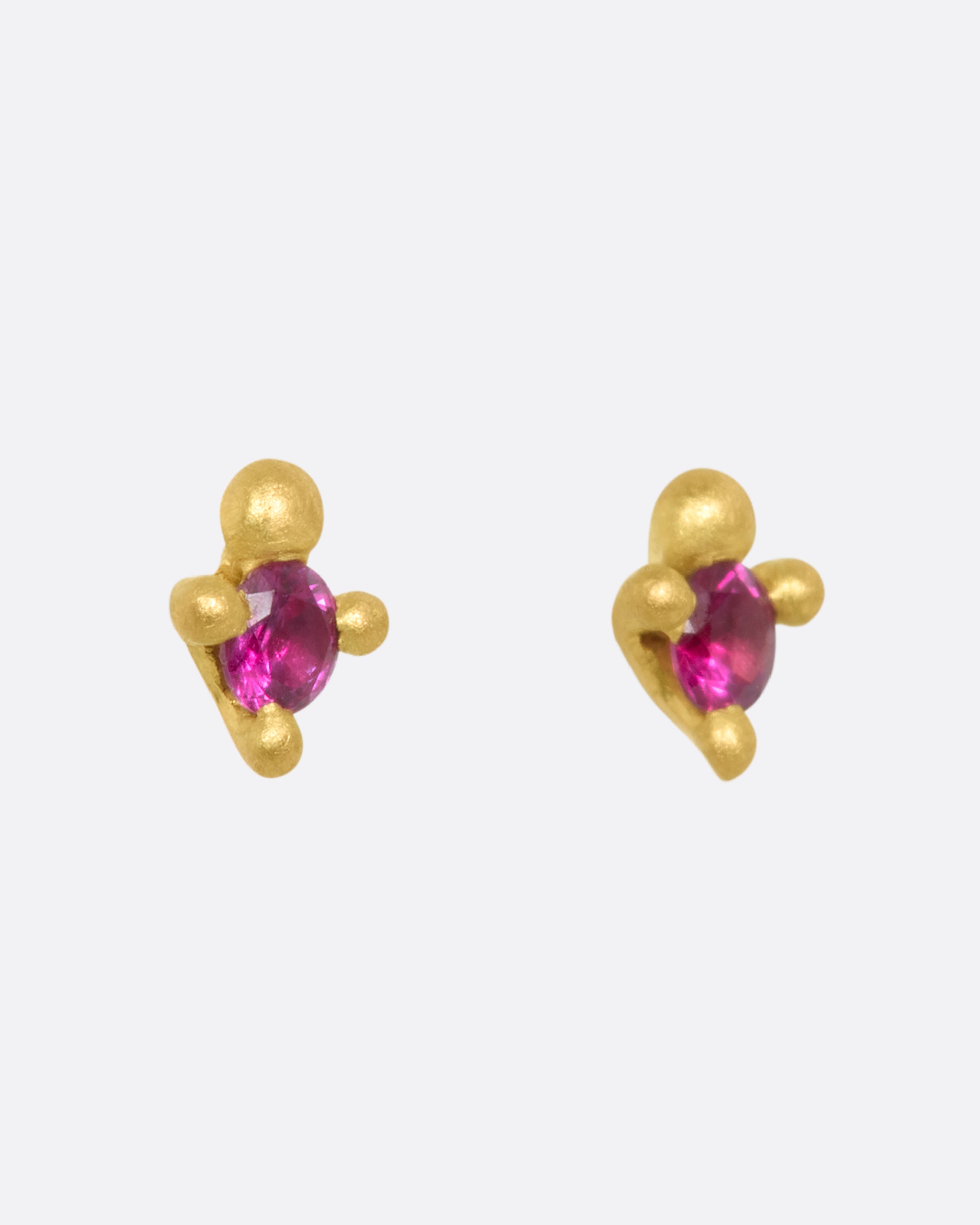 Yellow gold stud earrings with rubies. Shown from the side.