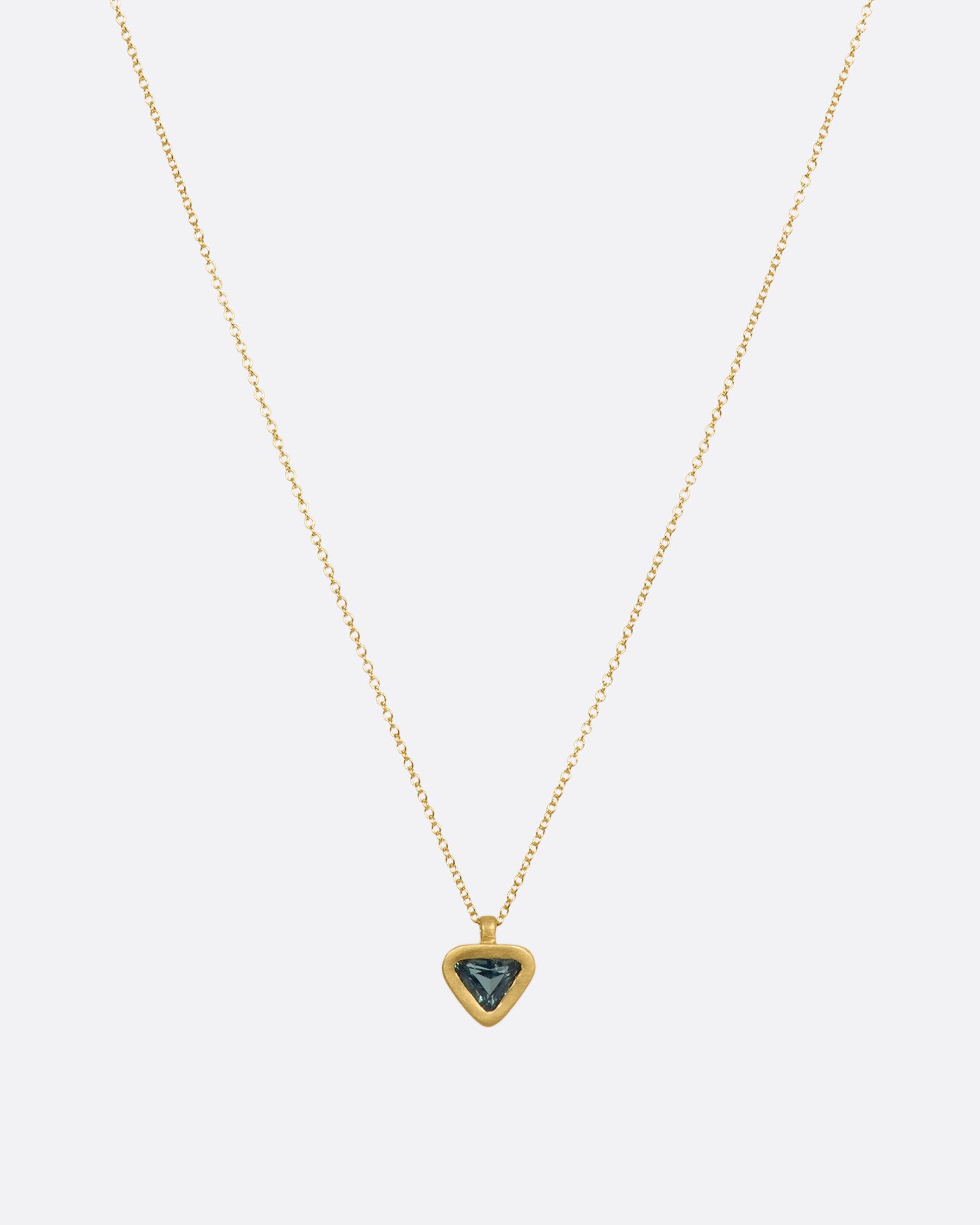 A yellow gold pendant with a triangle green sapphire pendant. View from the front with more chain.