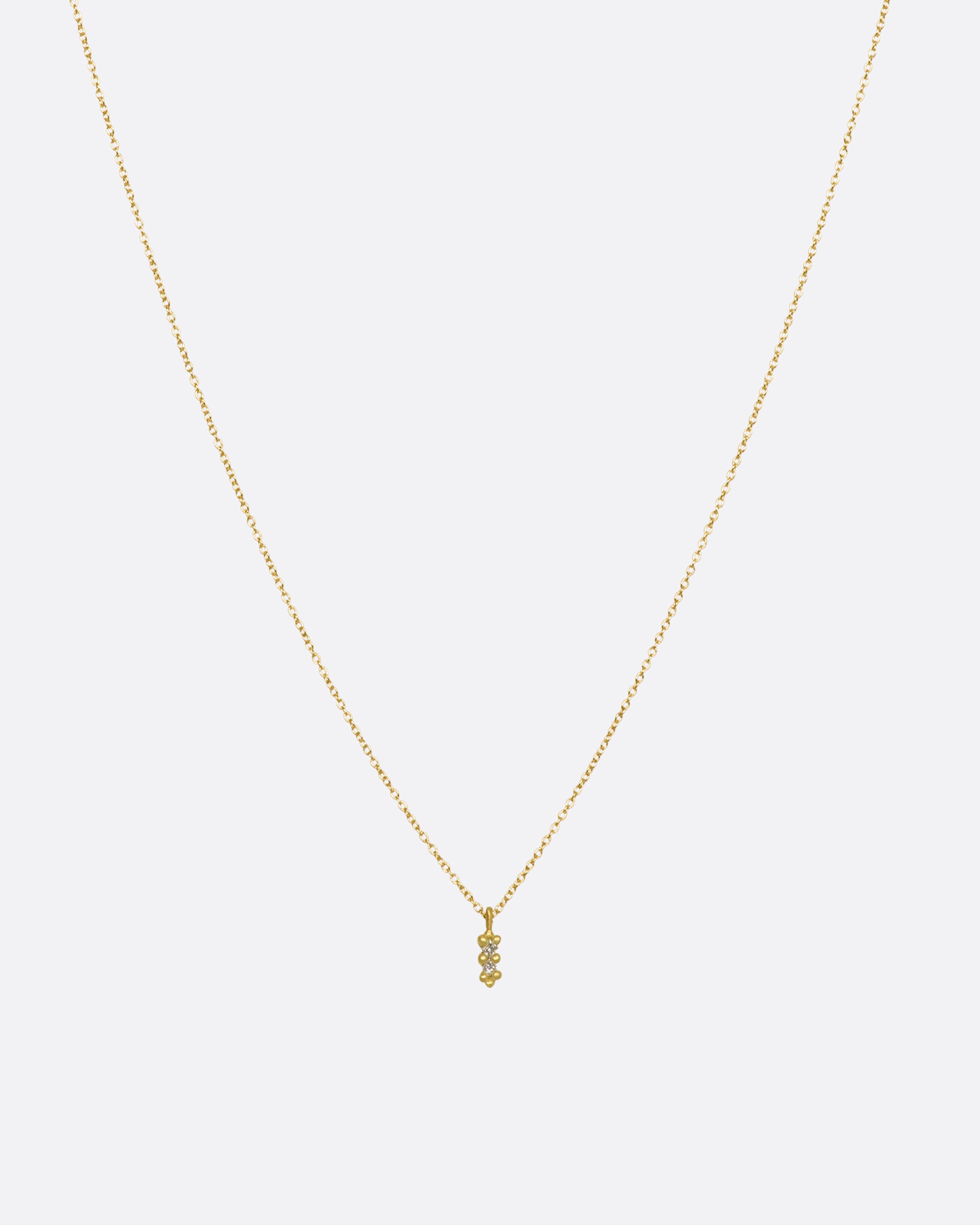 A yellow gold necklace with a double white diamond pendant. Shown from the front.