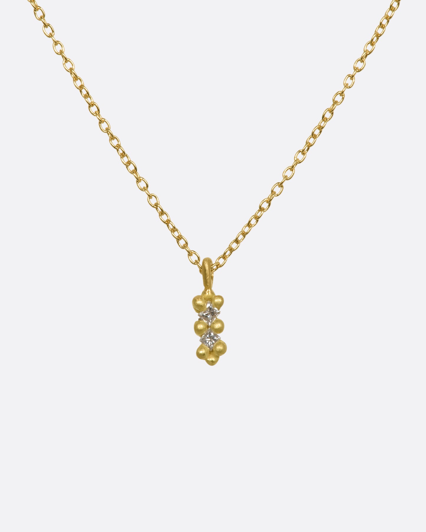 A yellow gold necklace with a double white diamond pendant. Shown from the front.