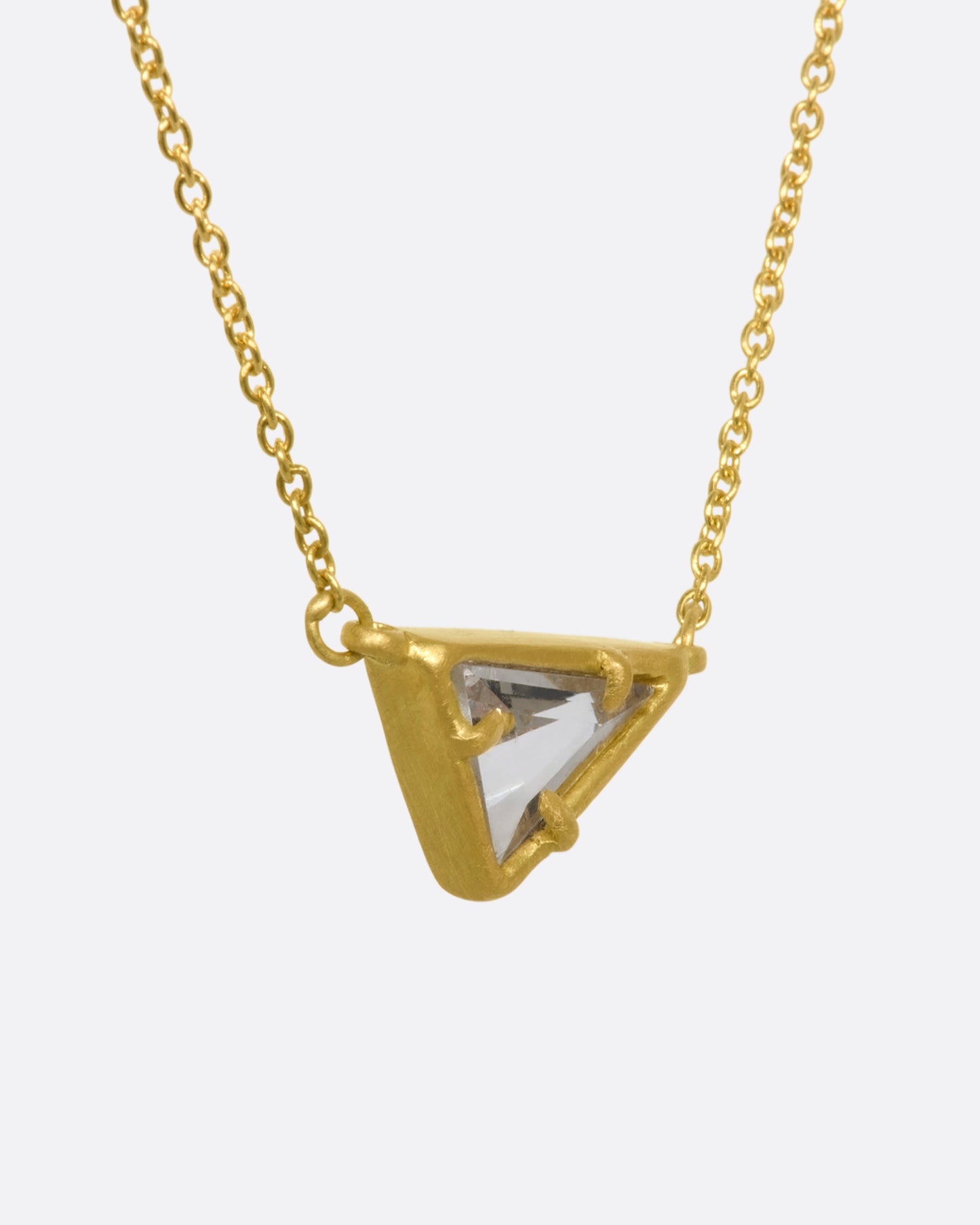 A yellow gold necklace with a triangular goshenite pendant. View from the side.