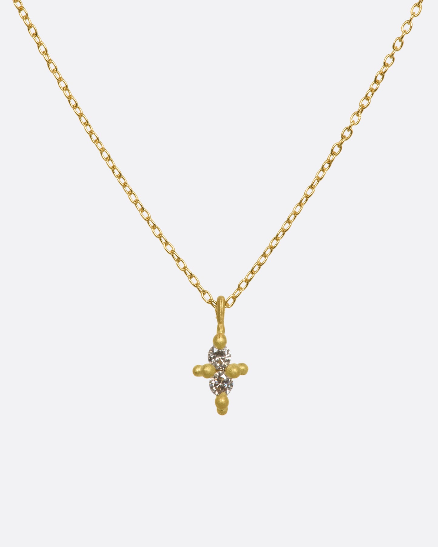 A yellow gold necklace with a double white diamond pendant. Shown from the front.