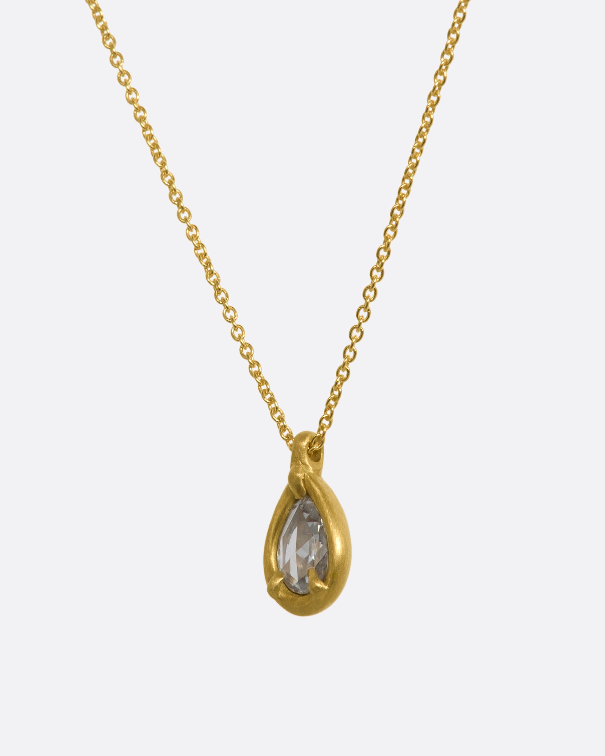 A yellow gold necklace with a rose cut teardrop shaped diamond pendant. Shown from the side.