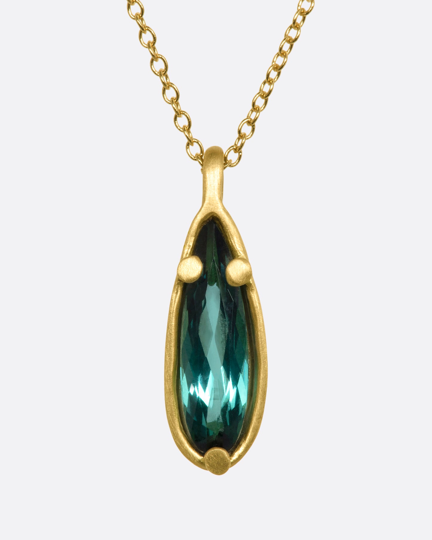 A matte yellow gold necklace with a large pear shaped teal tourmaline pendant. View from the front.