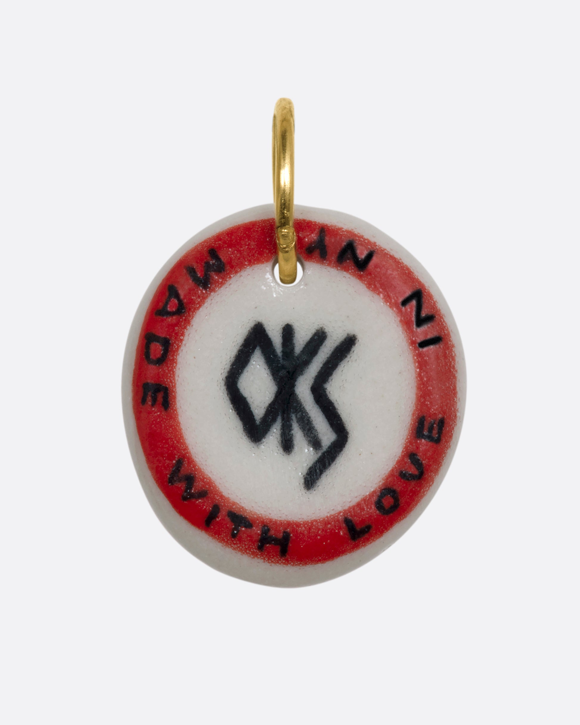 A hand painted porcelain charm with a blond woman in a bikini surfing on it and the words "Amagansett New York". View from the back. 