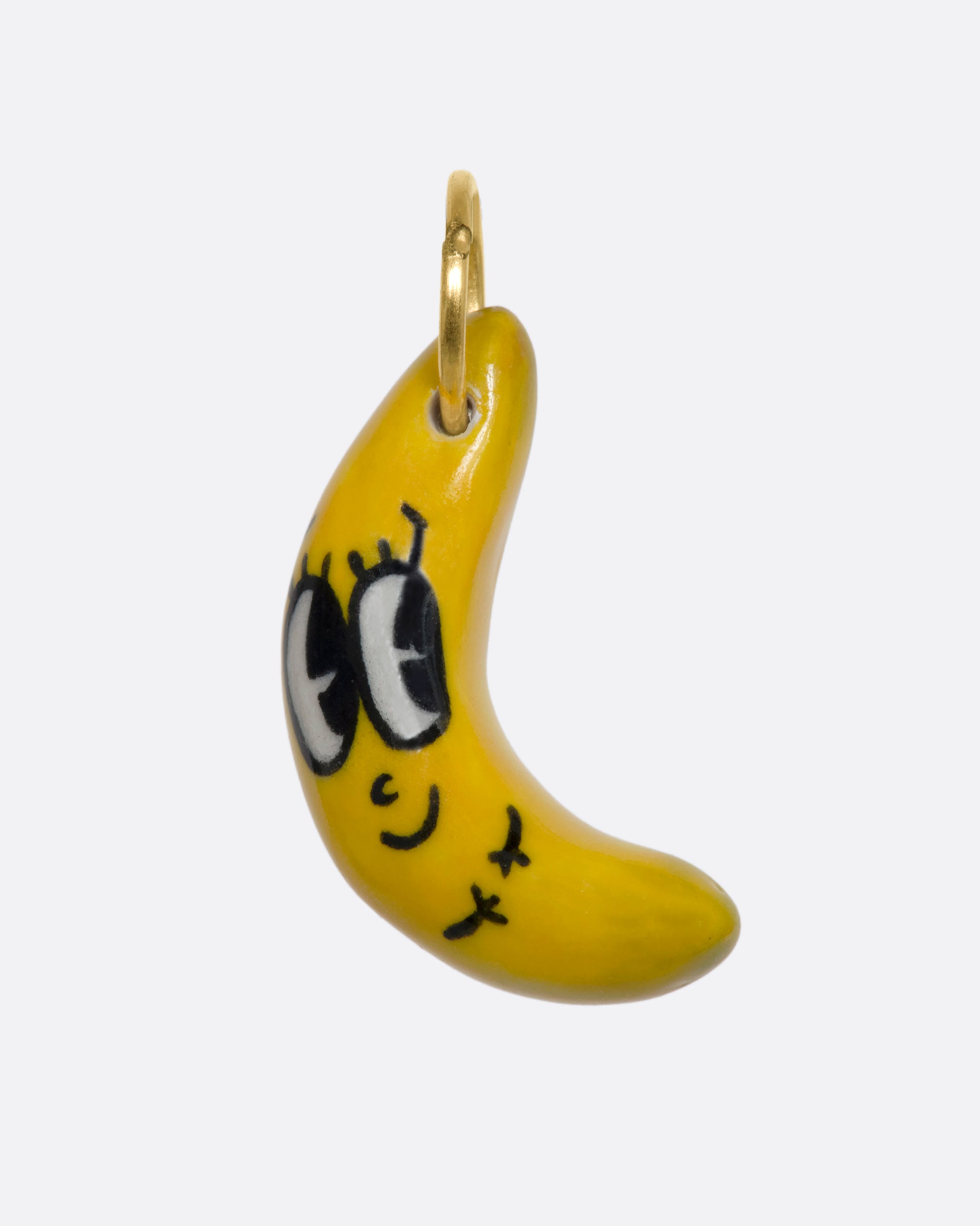 A yellow banana charm with a face and yellow gold bale. View from the front.