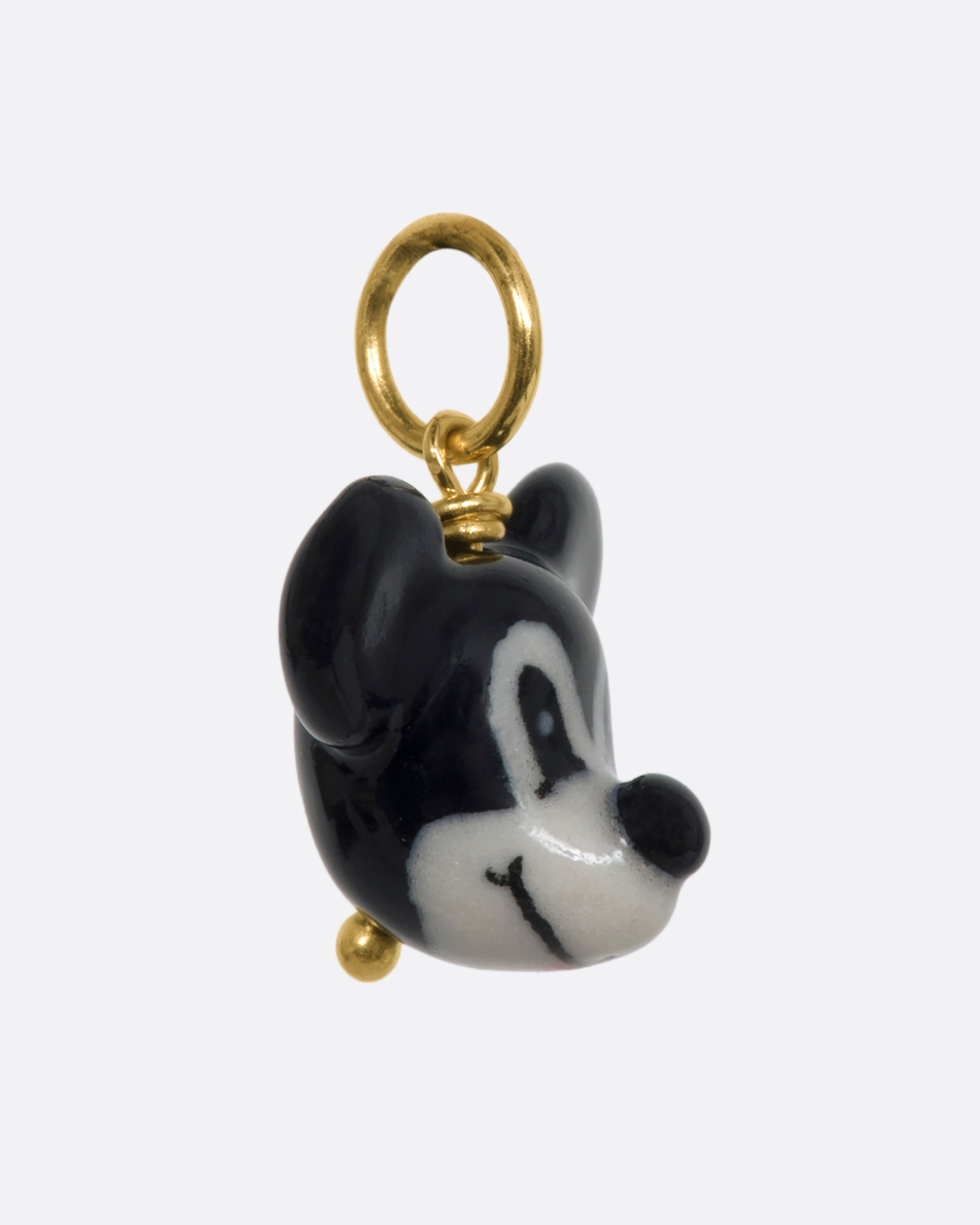 A three dimensional black and white era mickey mouse charm with a yellow gold bail. View from the side.