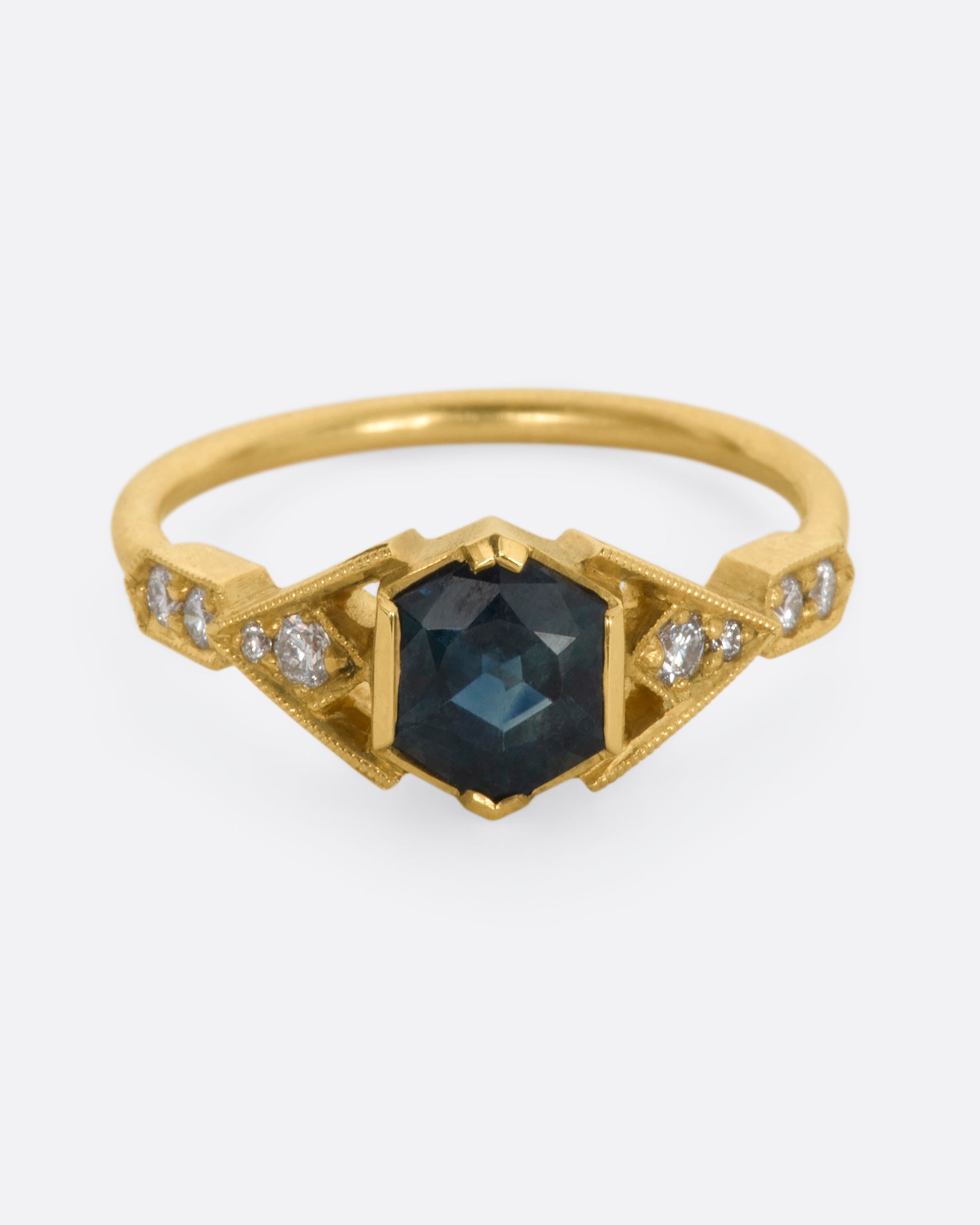 A yellow gold ring with deep teal sapphire and diamonds. View from the front.