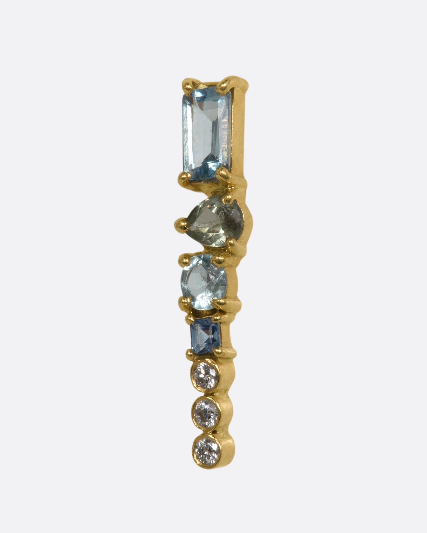 A yellow gold stud earring with a mosaic of aquamarine, tanzanite, apatite and diamonds. Shown from the side.