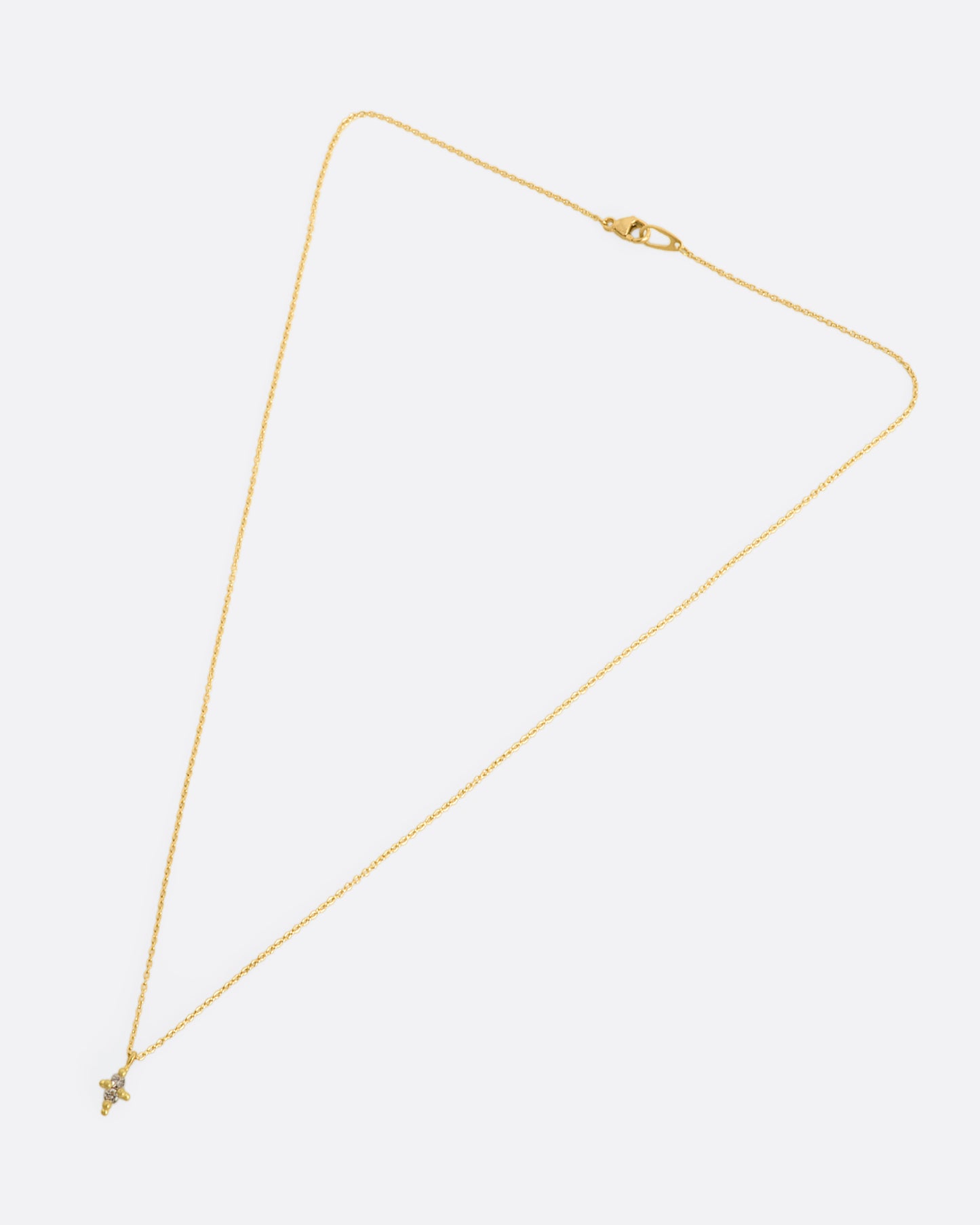 A yellow gold necklace with a double white diamond pendant. Shown laying flat.