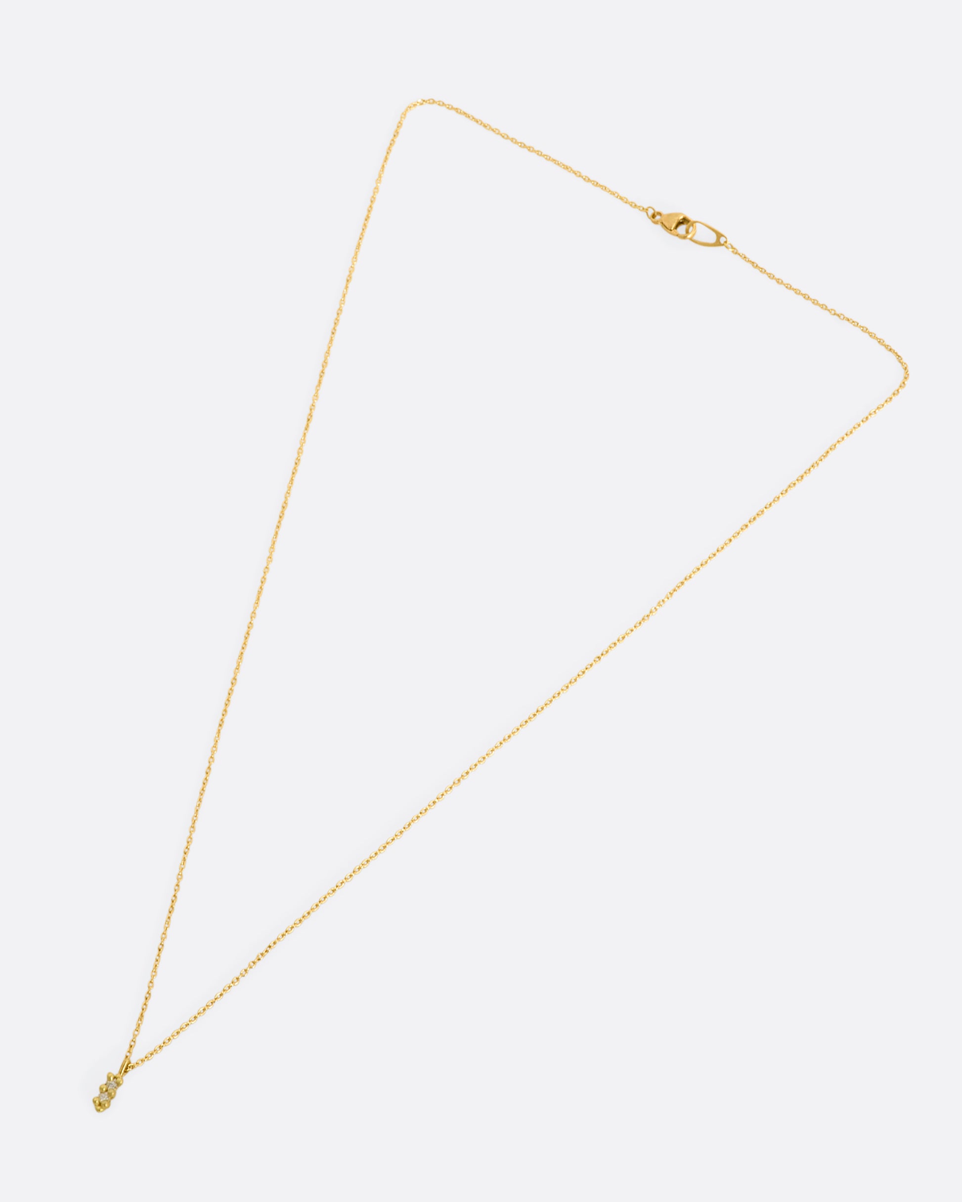 A yellow gold necklace with a double white diamond pendant. Shown laying flat.