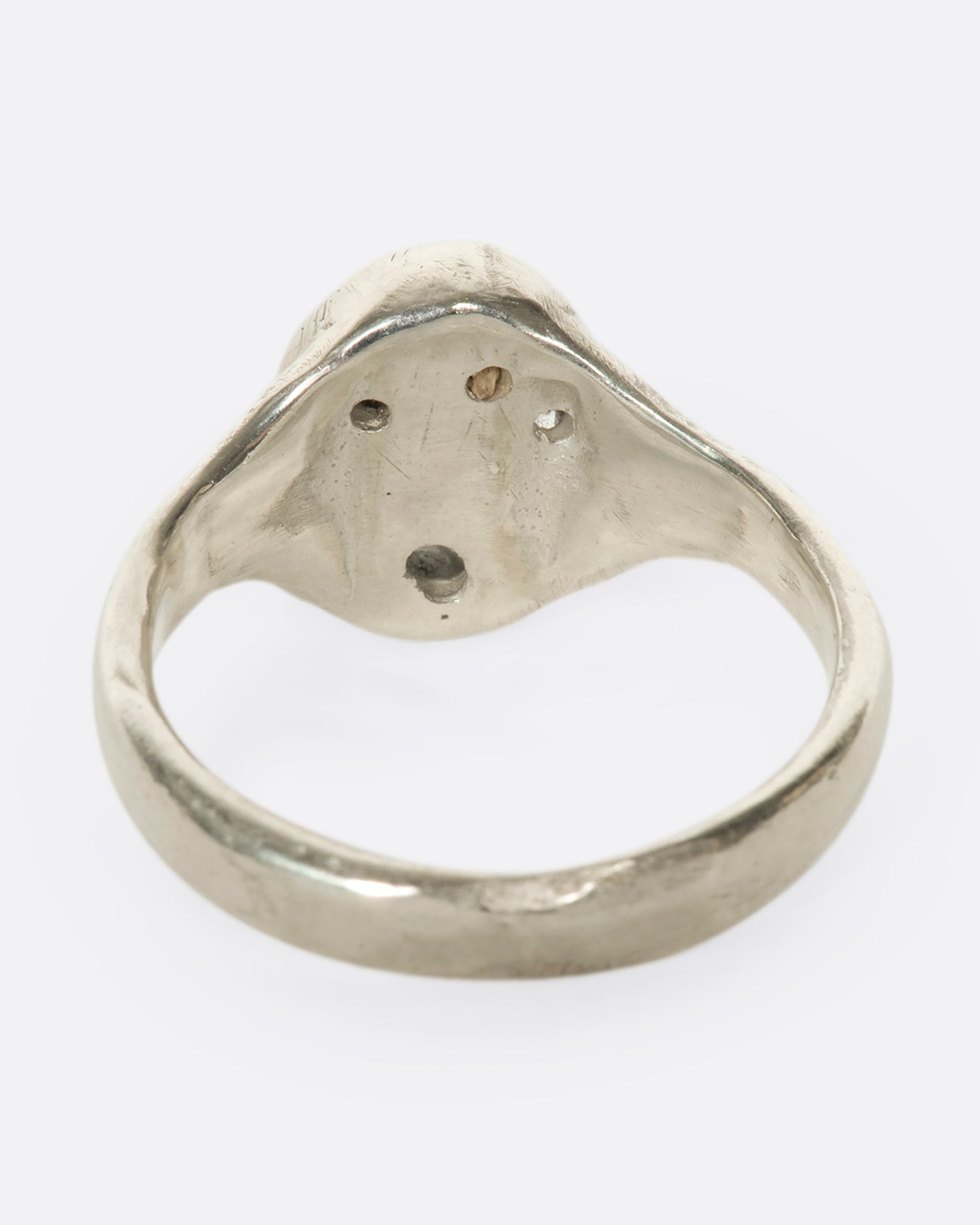 The underside view of an oval silver ring with grey diamonds.