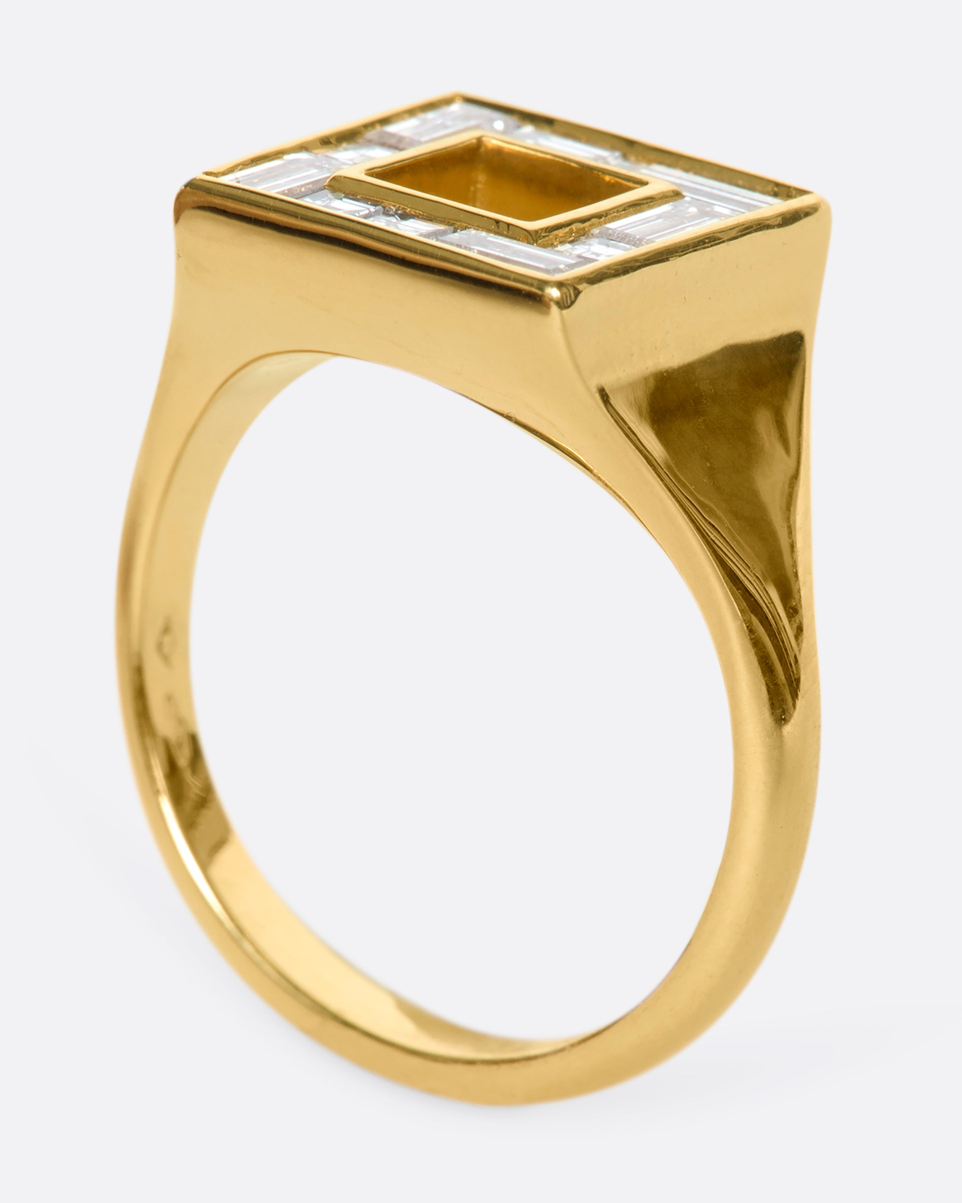 A photo of a square ring set with baguette diamonds standing on its band.