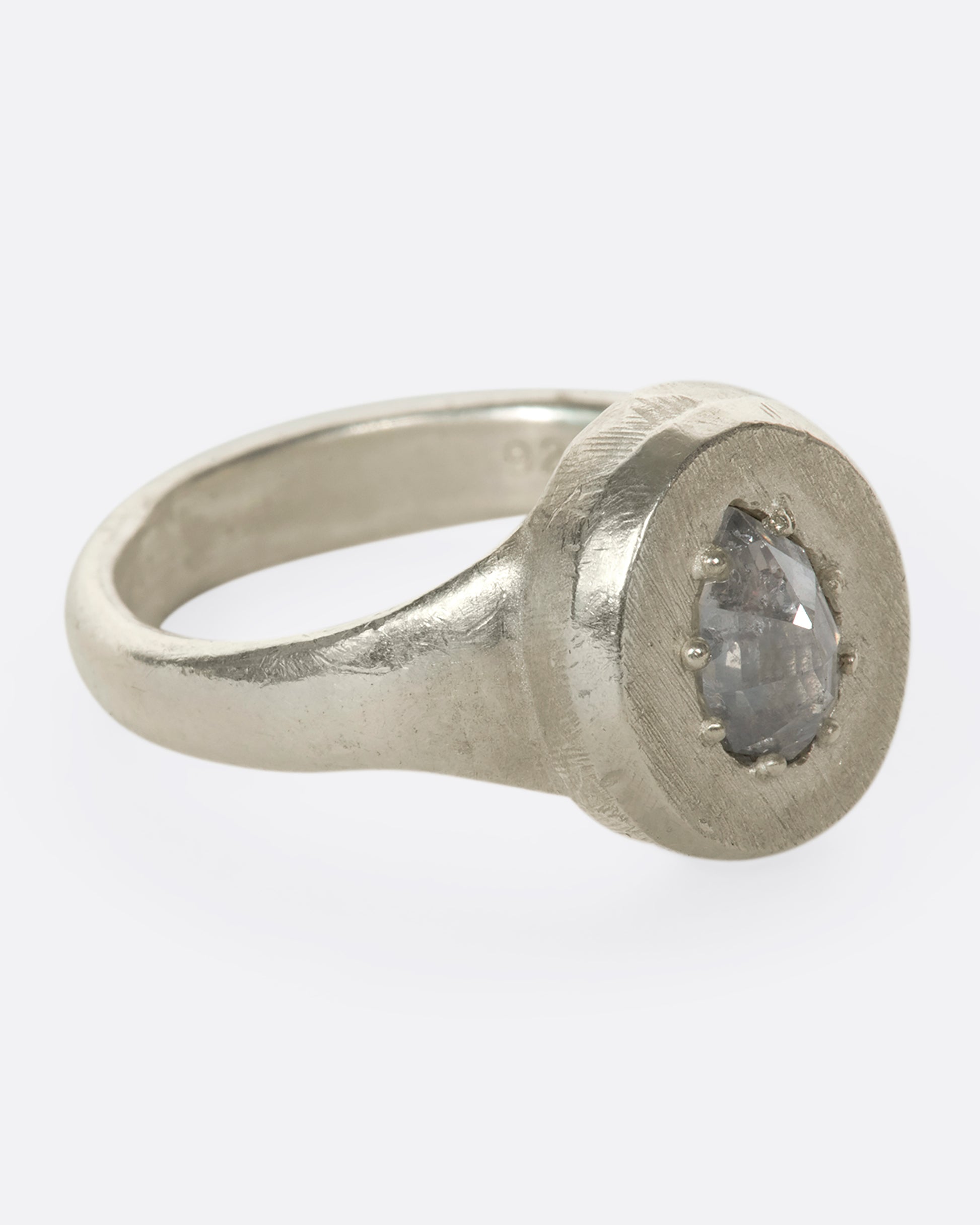 A sterling silver signet ring with a pear-shaped salt and pepper diamond secured with tiny prongs