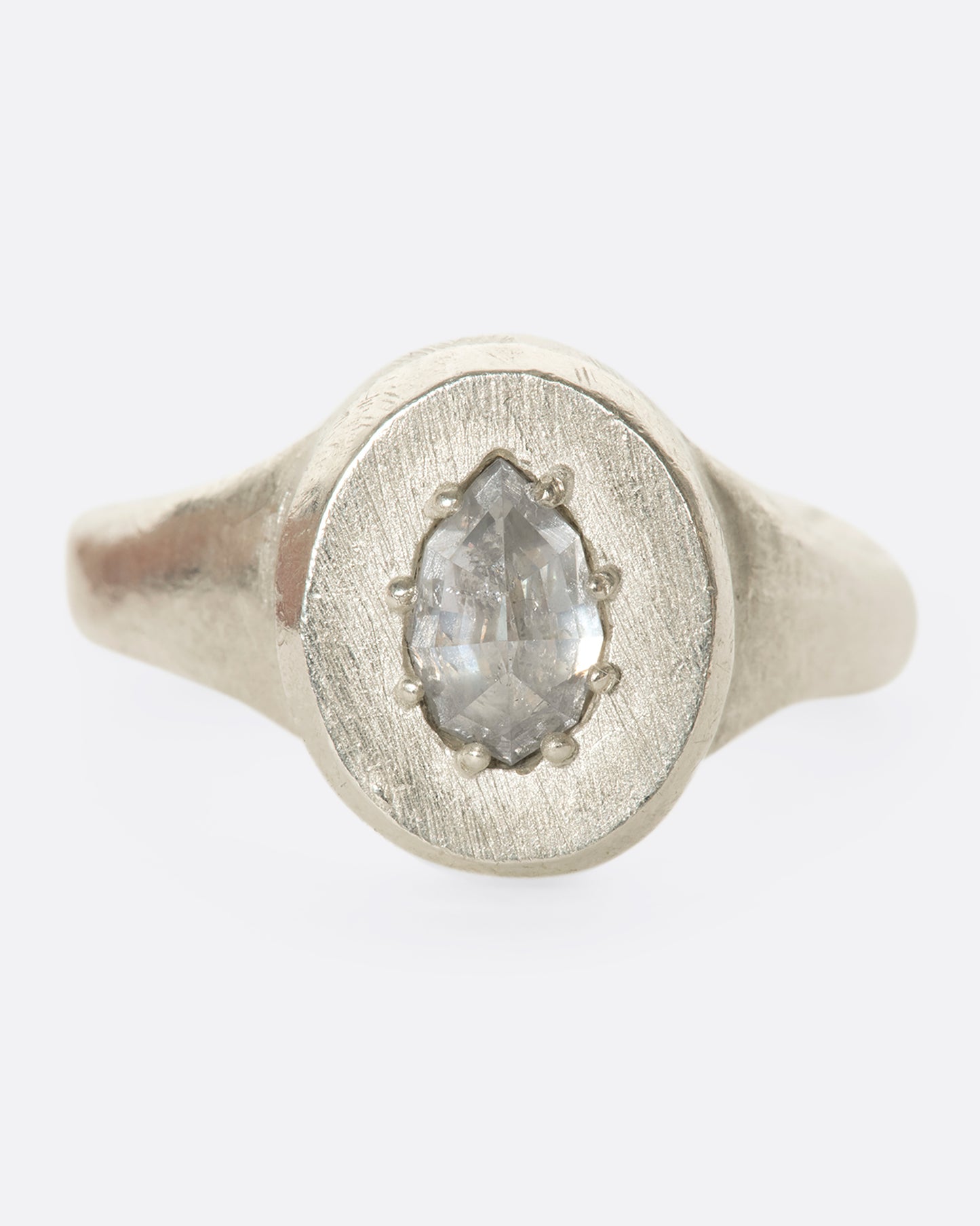 A sterling silver signet ring with a pear-shaped salt and pepper diamond secured with tiny prongs