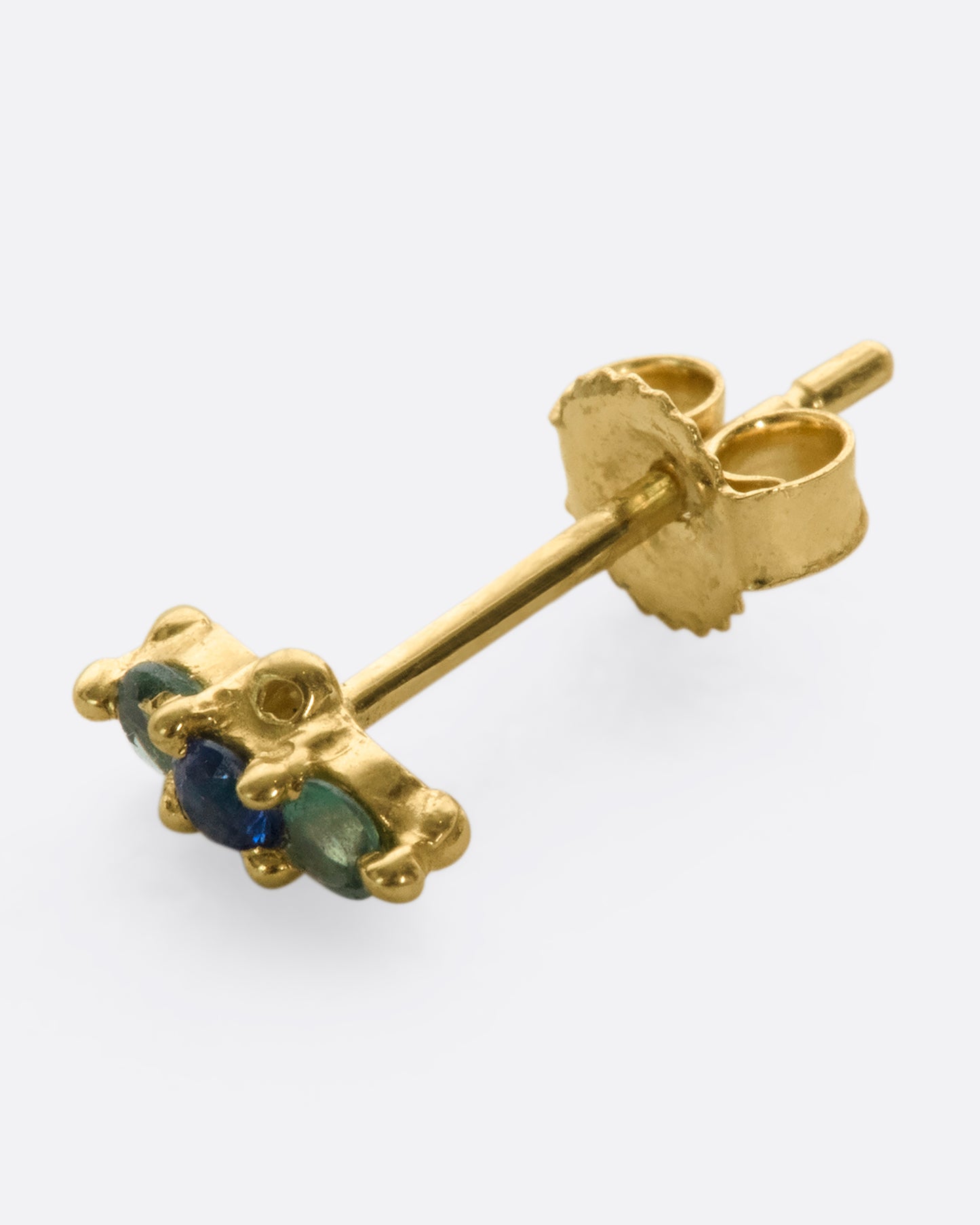 A 14k gold stud adorned with blue and green sapphires