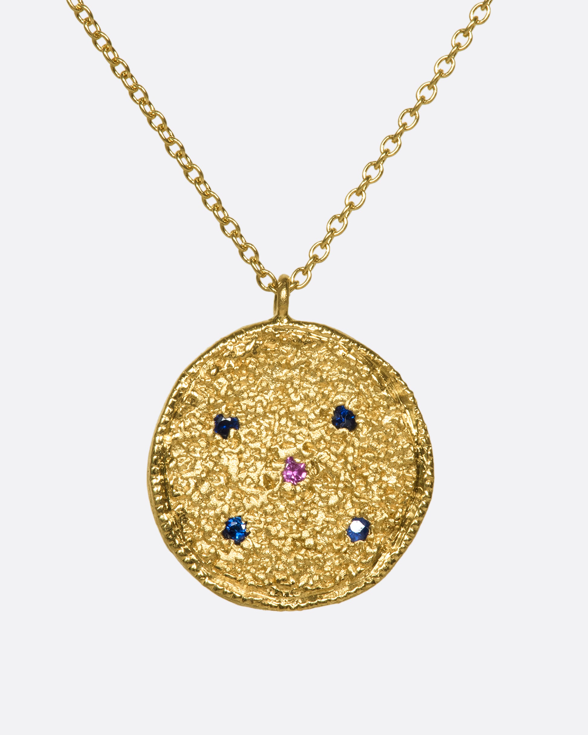 A textured disc pendant with blue and pink sapphires on a chain.