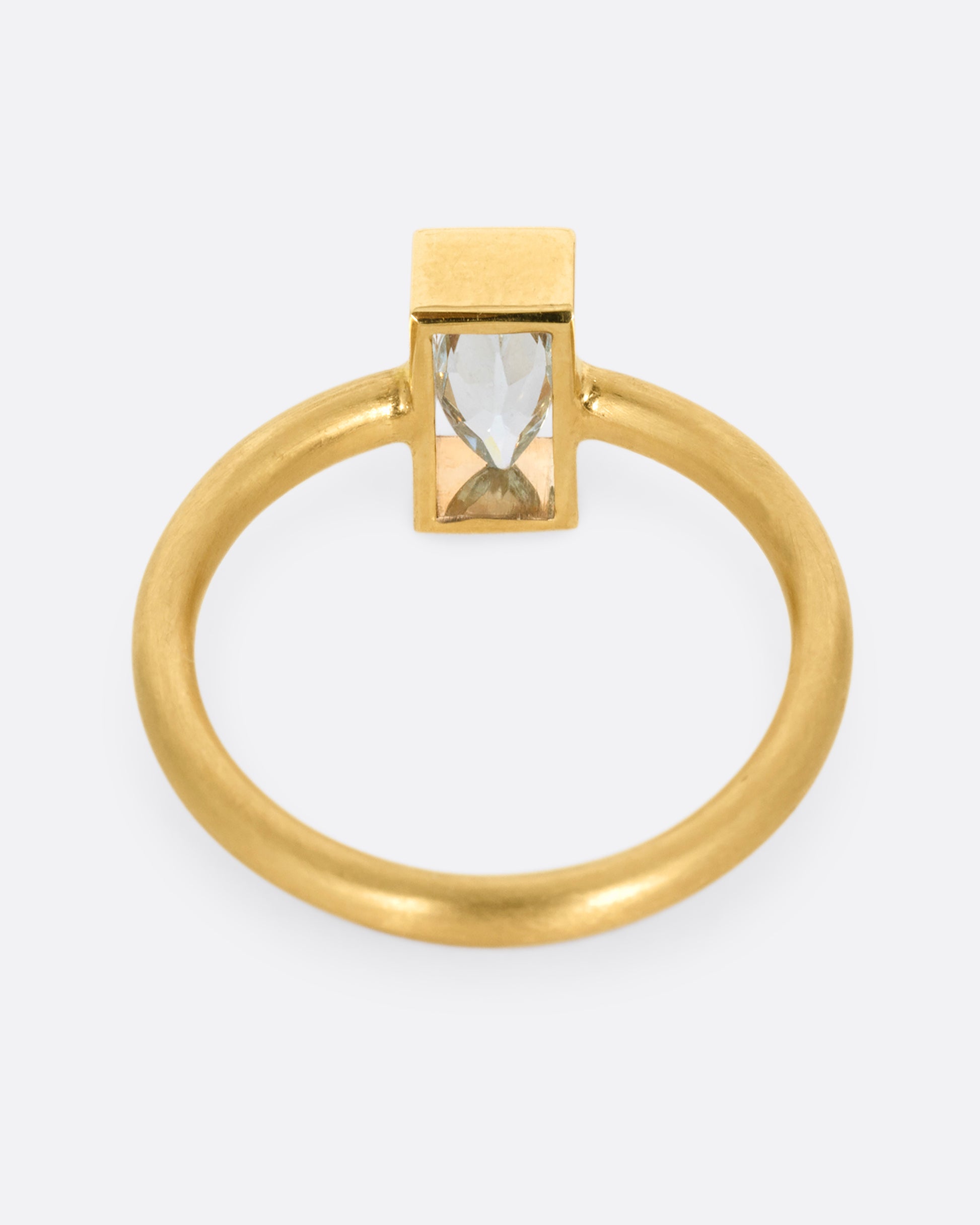 A yellow gold ring with an aquamarine in an open rectangular setting. Shown from the back.
