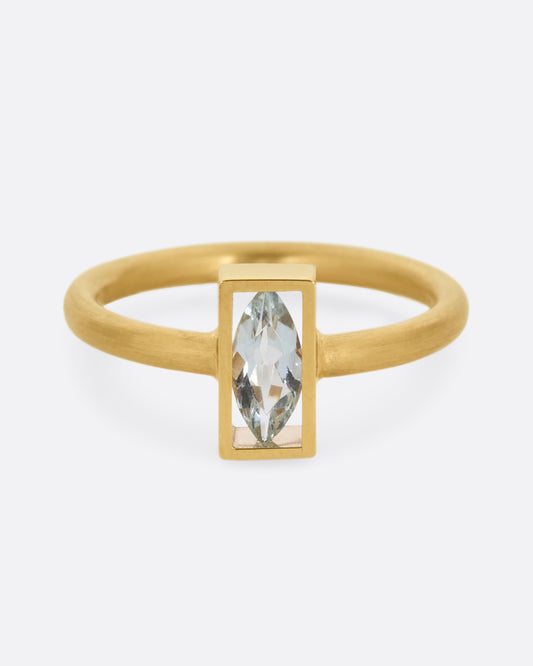 A yellow gold ring with an aquamarine in an open rectangular setting. Shown from the front.