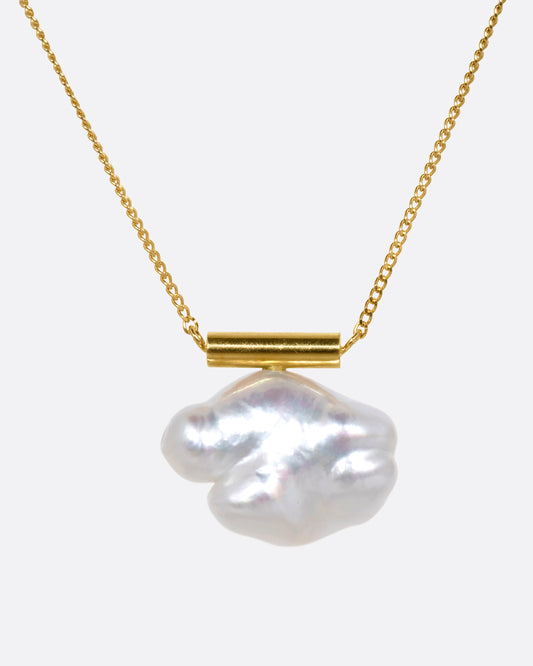 A yellow gold cable chain necklace with a gold bar and freeform pearl. Shown from the front.