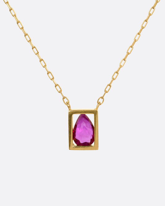 A yellow gold cable chain necklace with an open rectangular setting and a teardrop shaped ruby. Shown from the front.