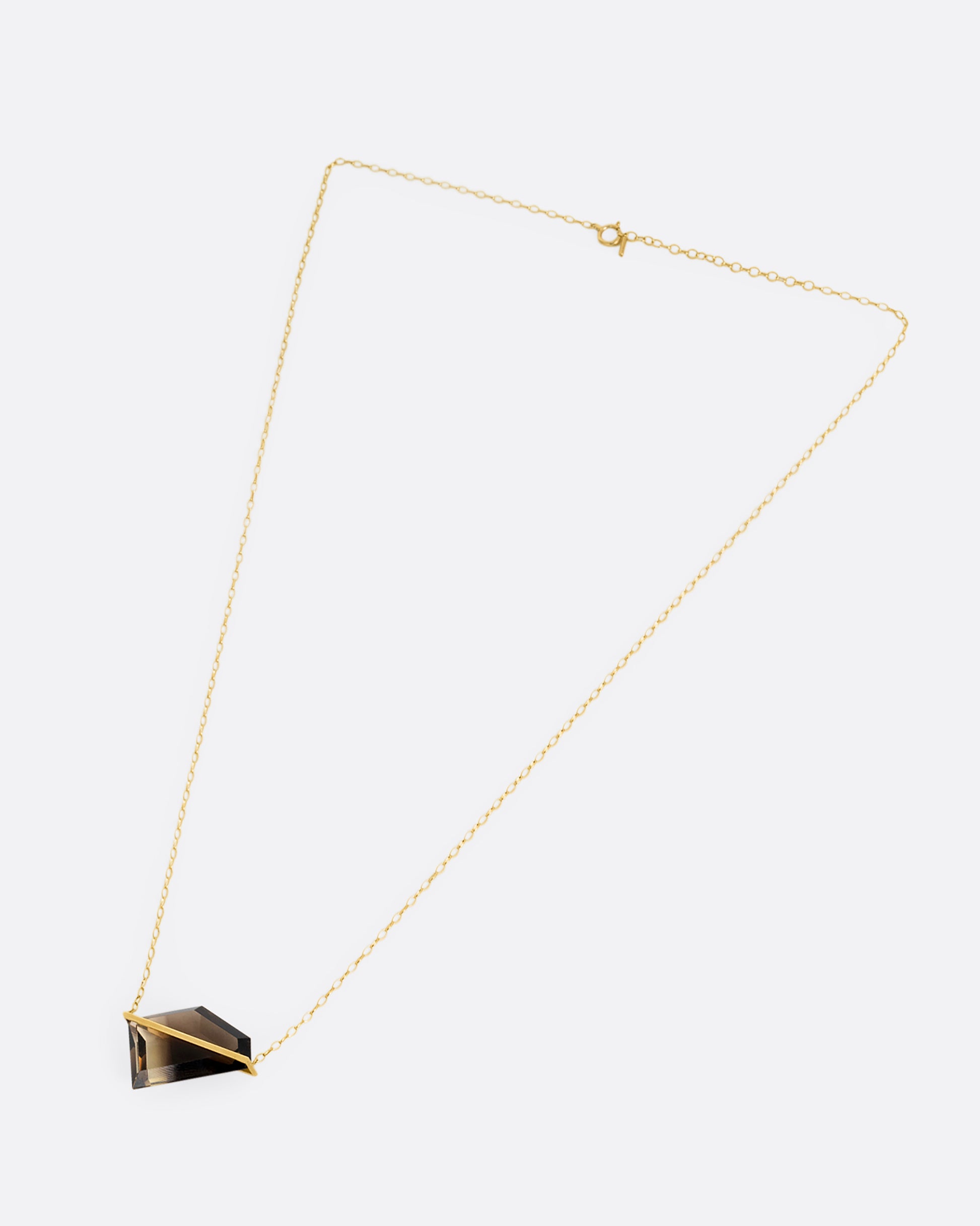 A yellow gold cable chain necklace with a sizable smoky quartz with an open gold bar setting, shown from the front.