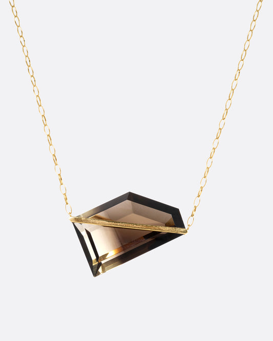 A yellow gold cable chain necklace with a sizable smoky quartz with an open gold bar setting, shown from the front.