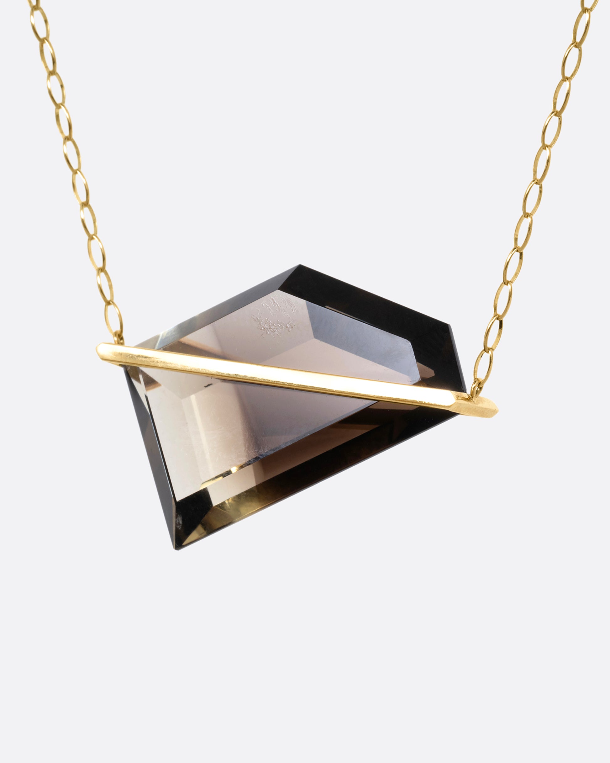 A yellow gold cable chain necklace with a sizable smoky quartz with an open gold bar setting, shown from the front.