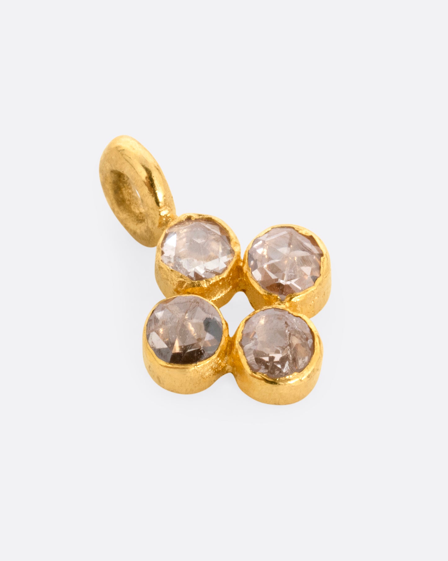 A yellow gold cross shaped charm with four diamonds. Shown lying flat.