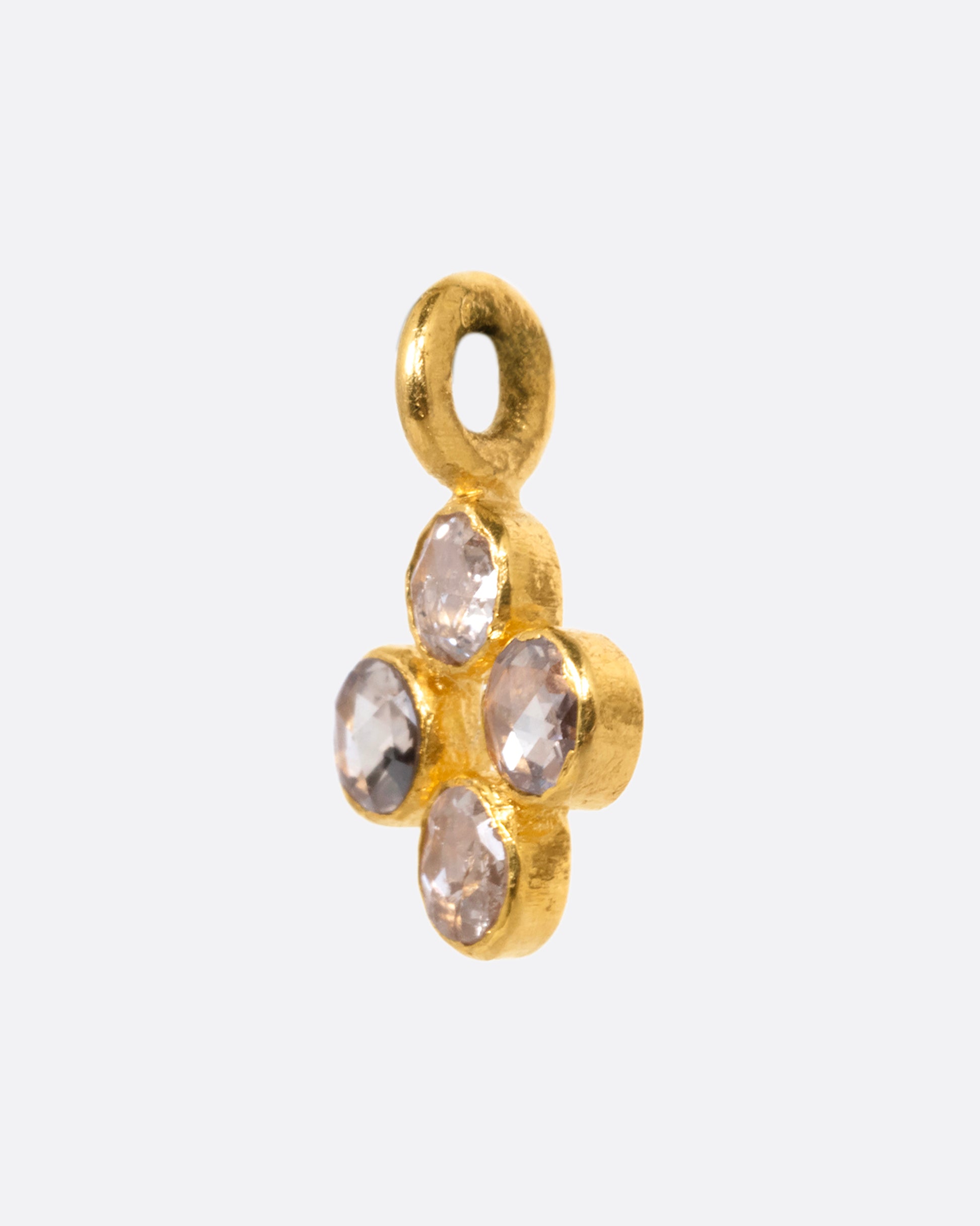A yellow gold cross shaped charm with four diamonds. Shown from the side.
