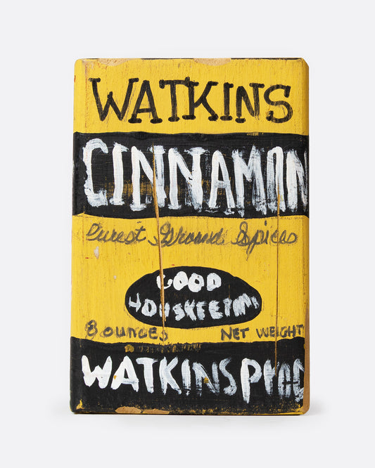 A yellow and black hand painted wooden box with the text 'WATKIN'S CINNAMON', shown from the front.