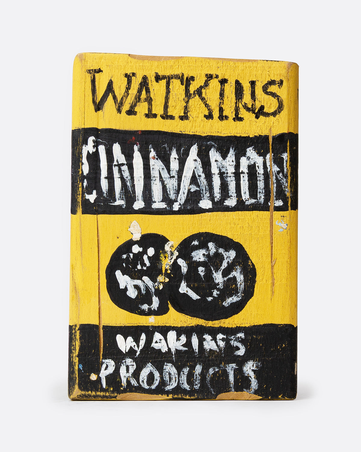 A yellow and black hand painted wooden box with the text 'WATKIN'S CINNAMON', shown from the back.
